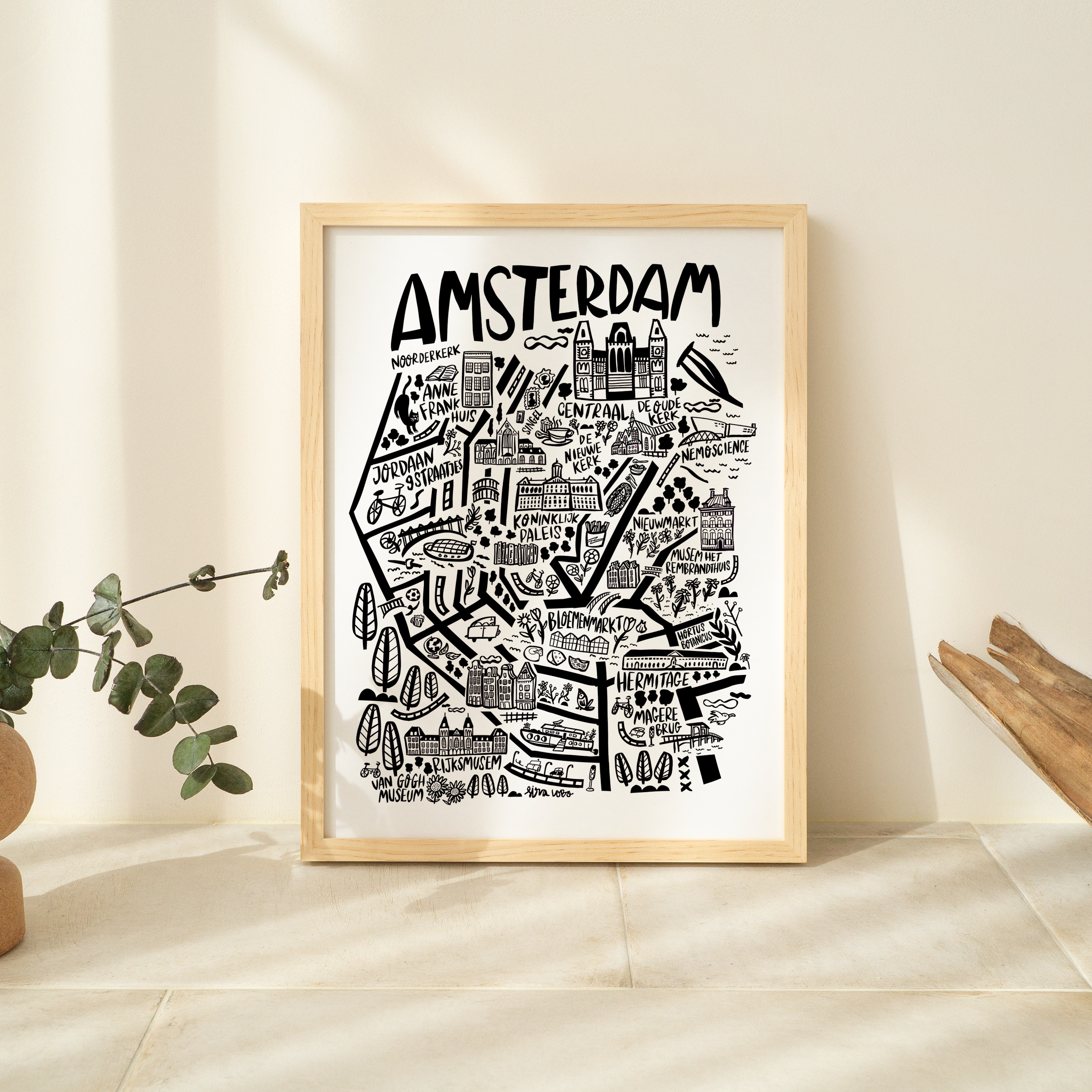 Framed map of Amsterdam on a white wall with decorative elements.