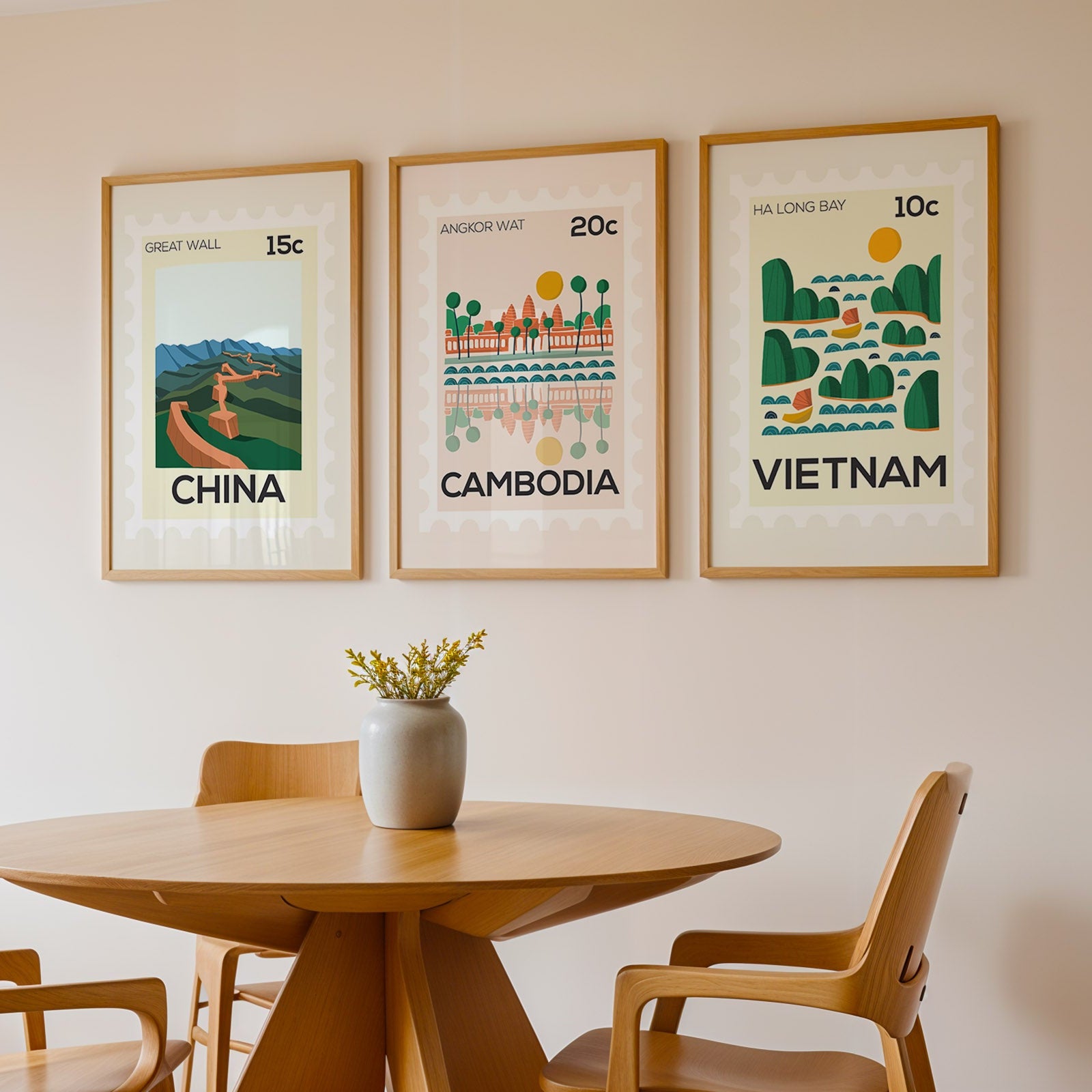 Three framed prints of China, Cambodia, and Vietnam on a wall above a wooden table with chairs.