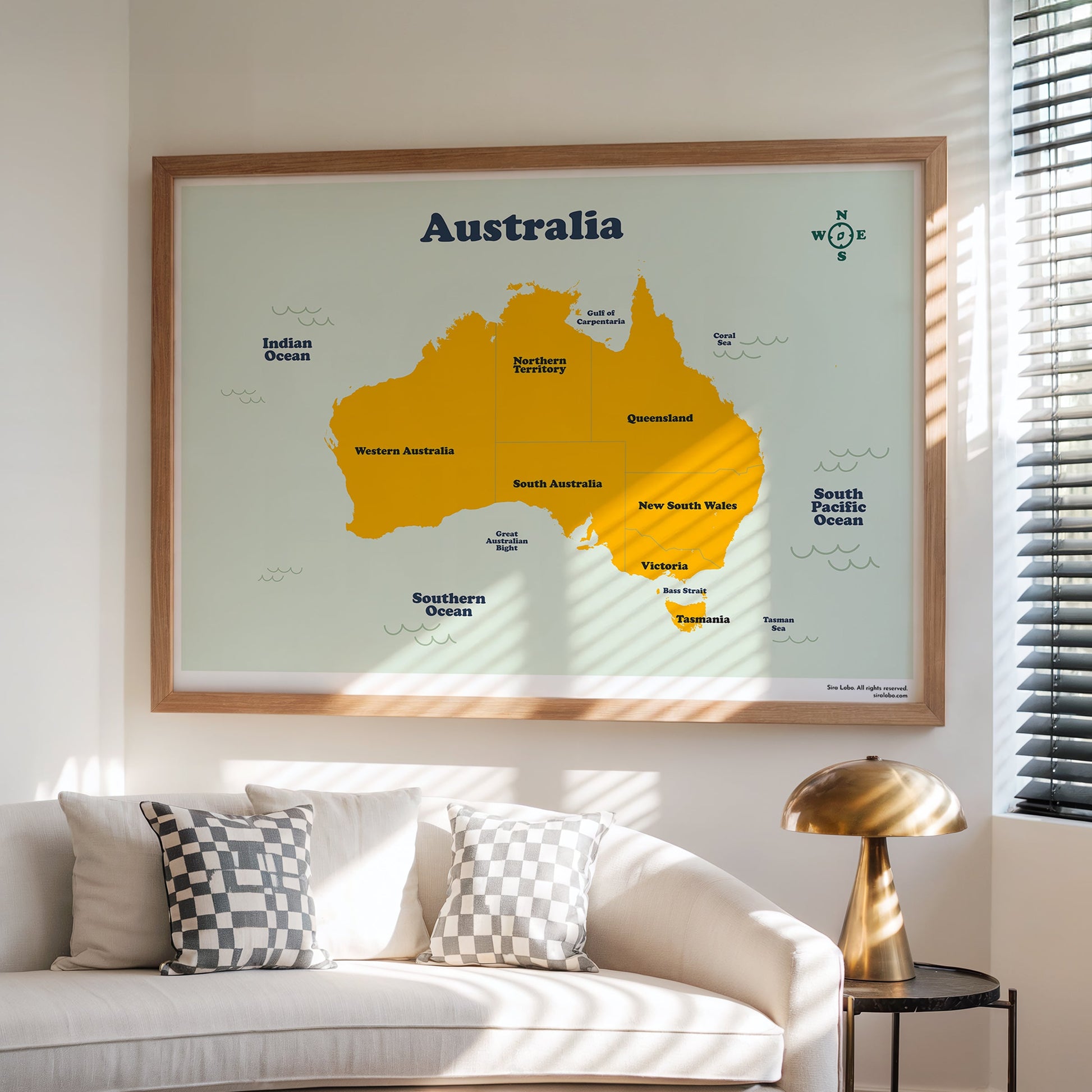 Framed map of Australia on a wall above a white sofa with decorative pillows.
