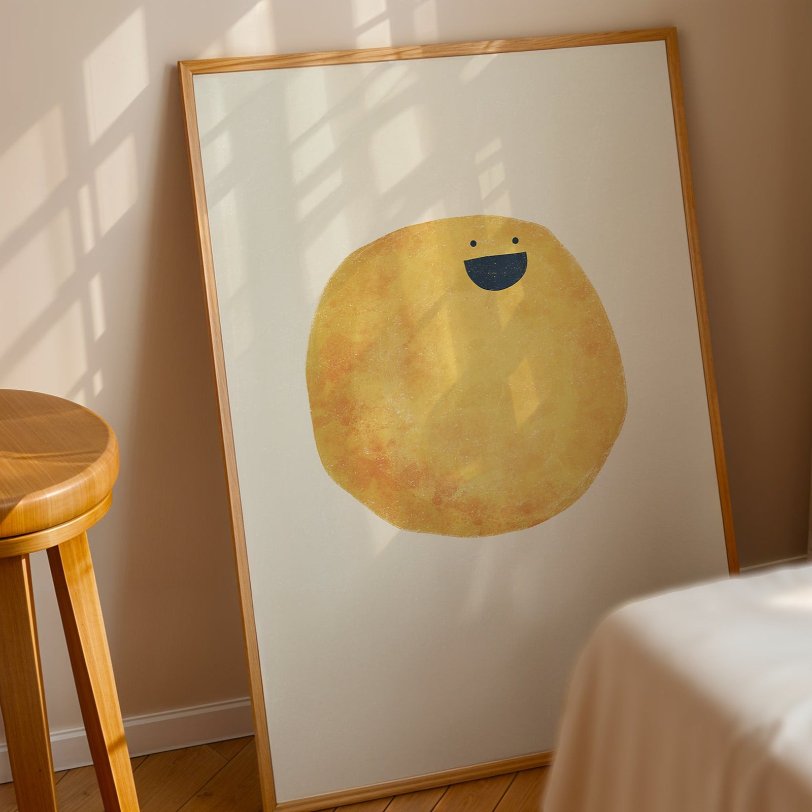 Framed artwork of a yellow character with a blue smile on a white wall.