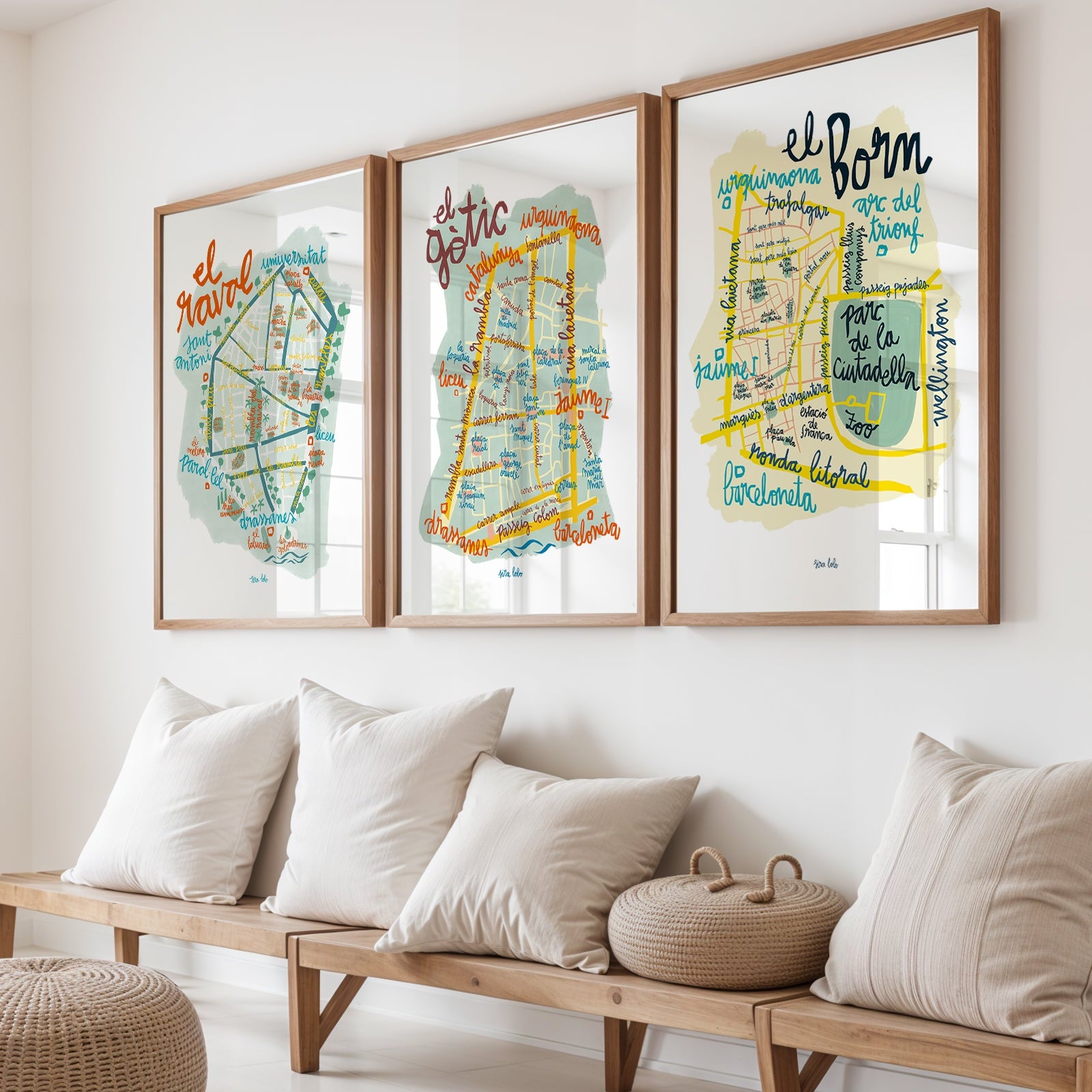 Three framed maps on a wall above a wooden bench with cushions.