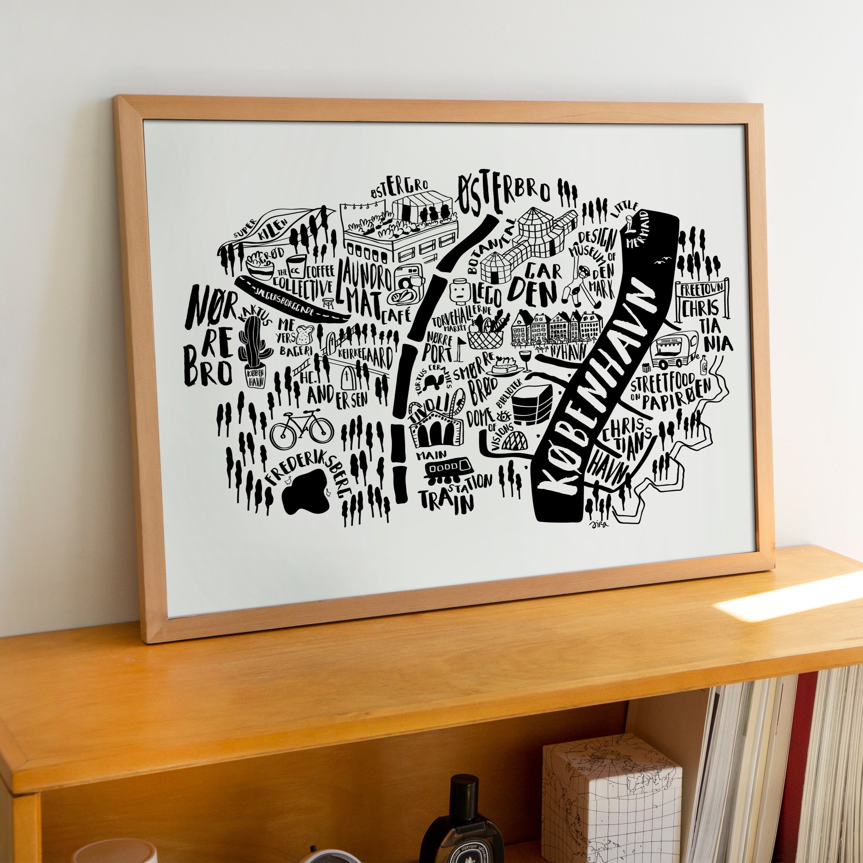 Framed black and white map print on a wooden shelf against a white wall
