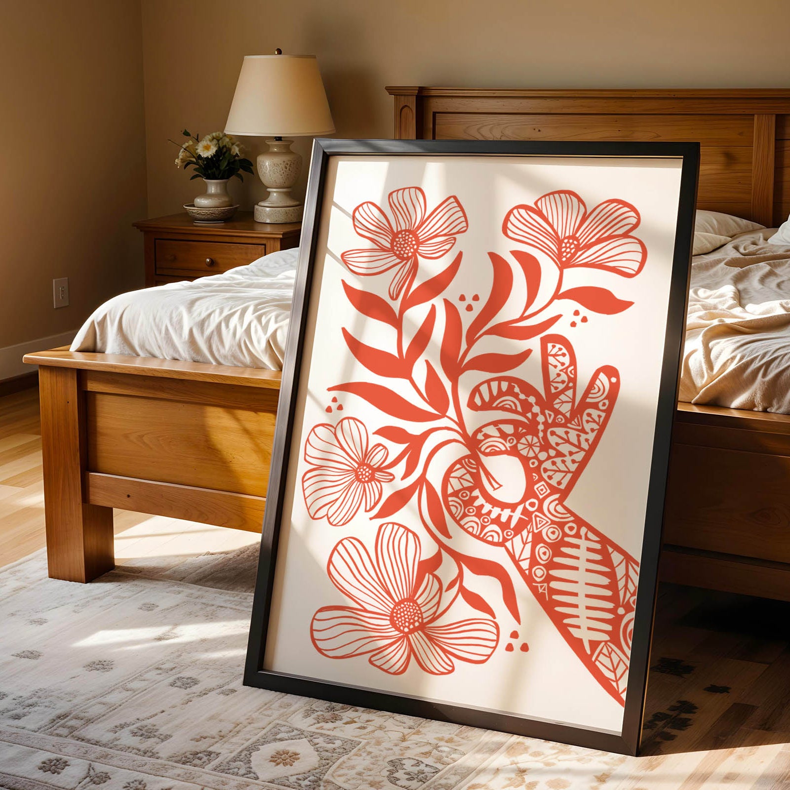 Framed artwork with red floral design on a bed in a bedroom