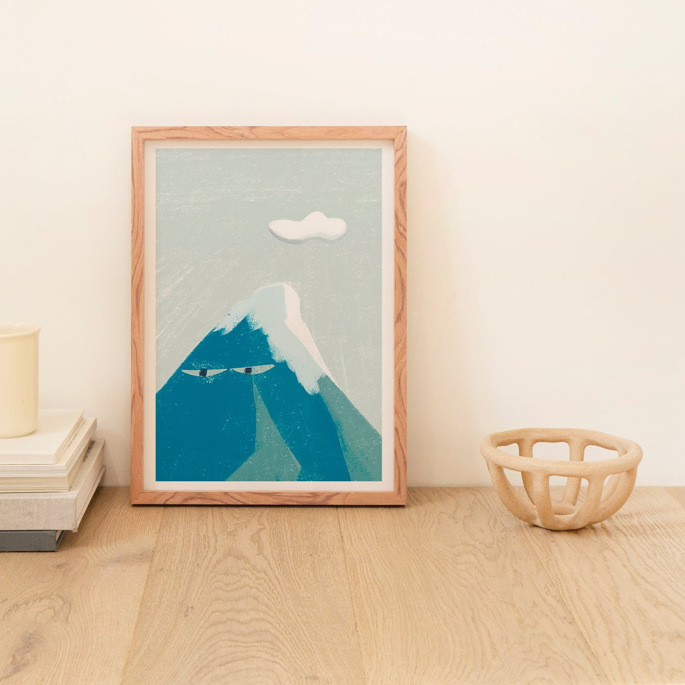 Framed artwork of a mountain on a wooden surface with minimal decor