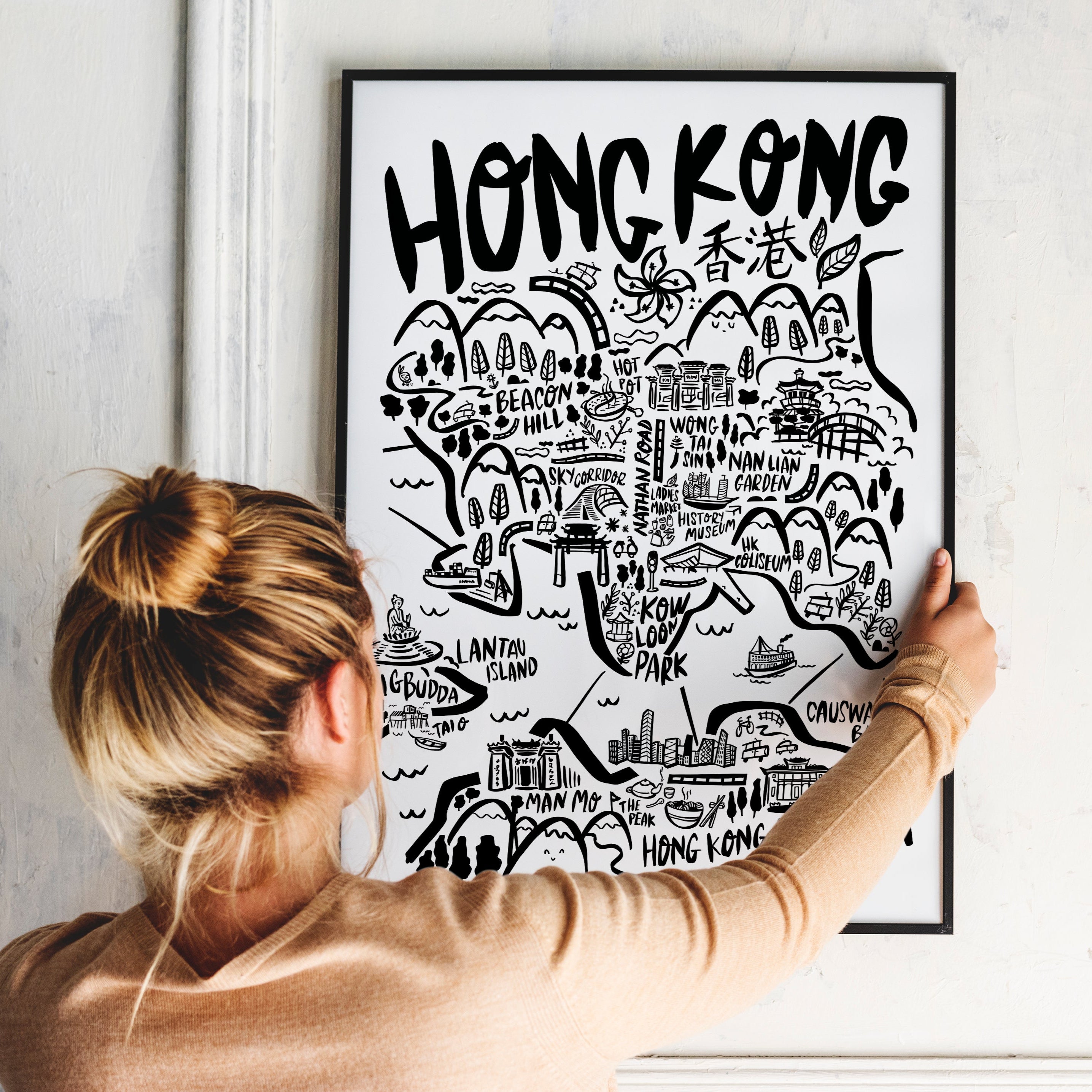 Person holding a framed map of Hong Kong against a white wall