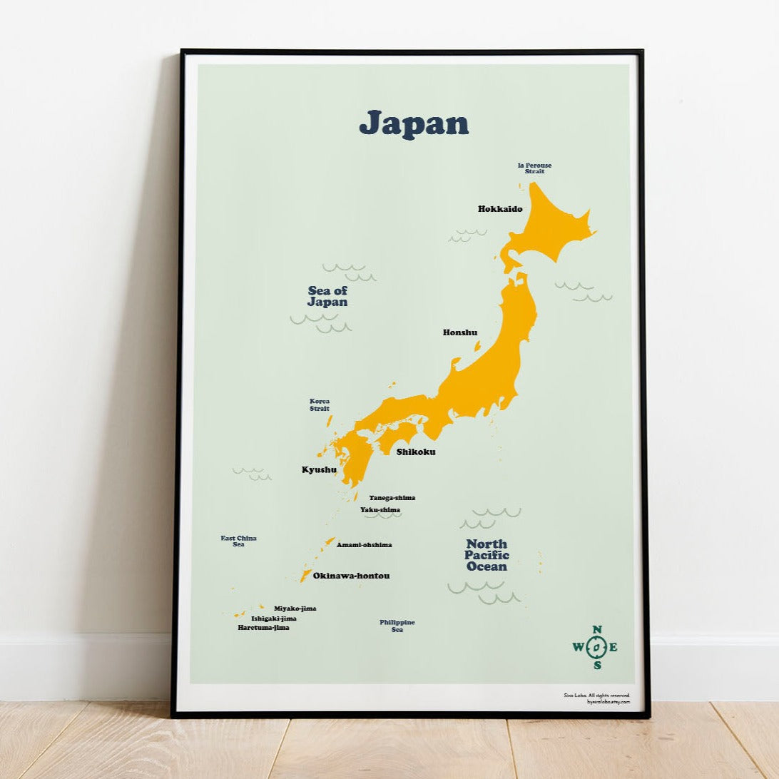 A printable map of Japan with main islands name and geographical spots, displayed in a frame on a white wall.
