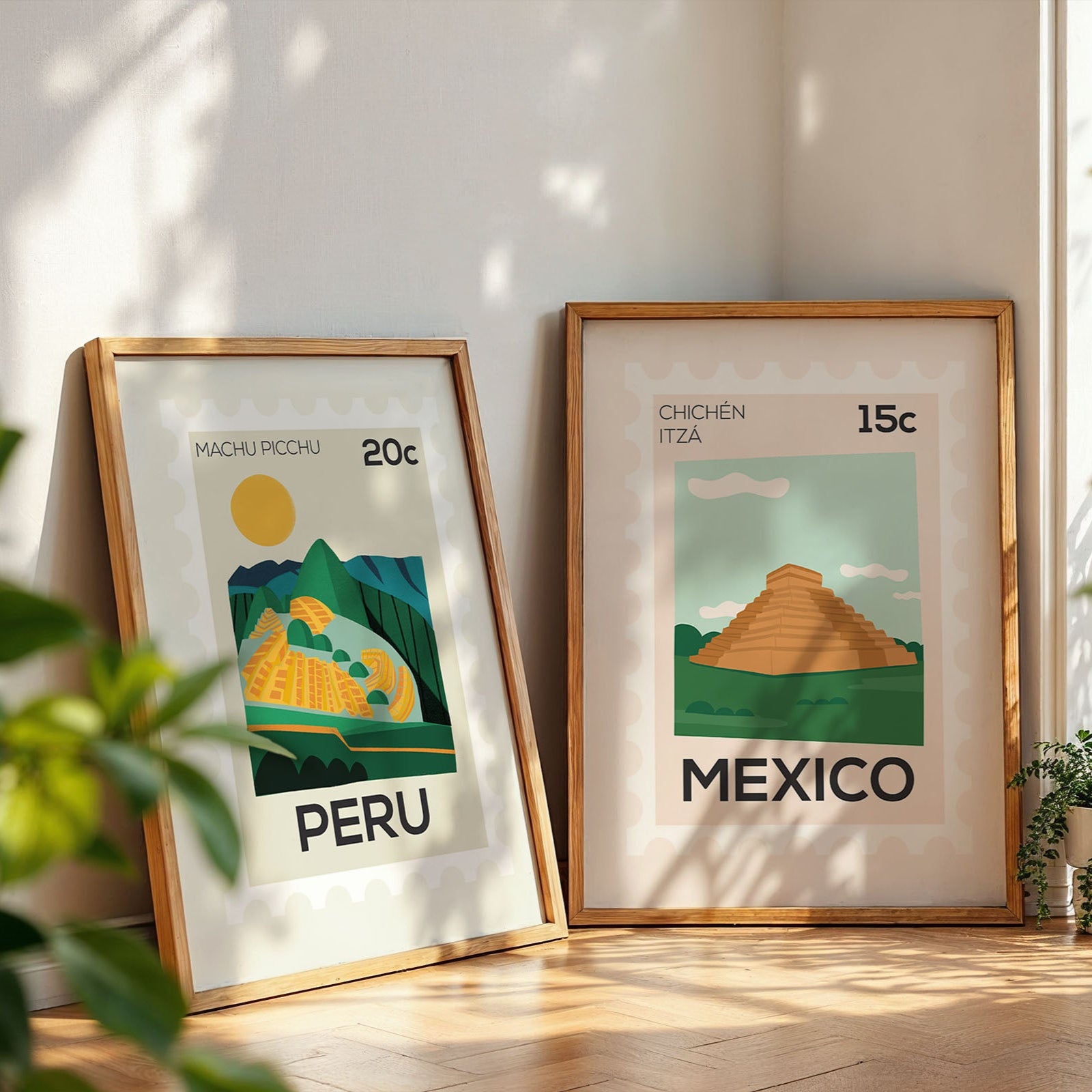 Two framed posters of Peru and Mexico on a light wooden floor with plants around.