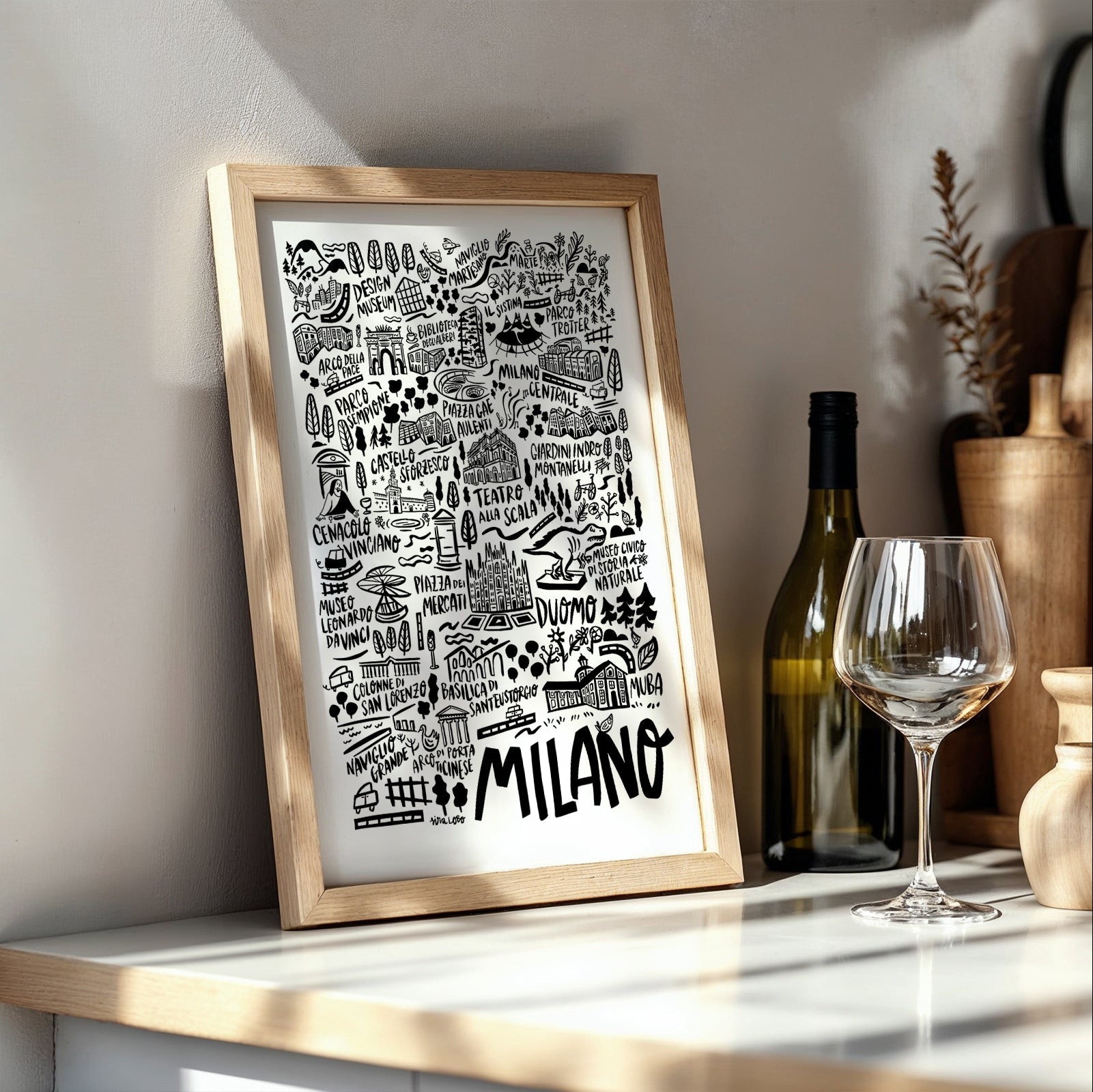Framed artwork with 'Milano' on a shelf with wine bottle and glass