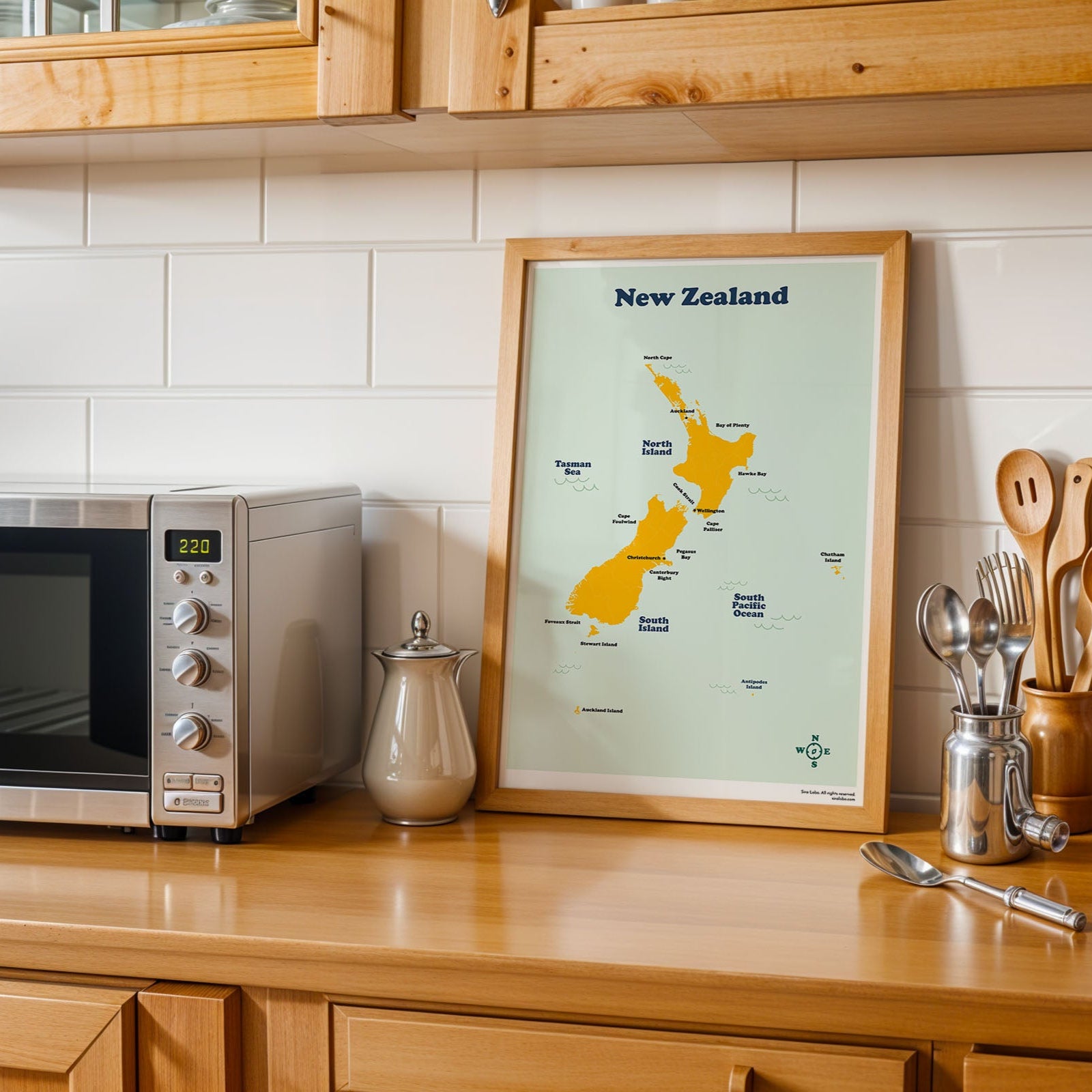 Kitchen counter with a map of New Zealand, microwave, and kitchen utensils.
