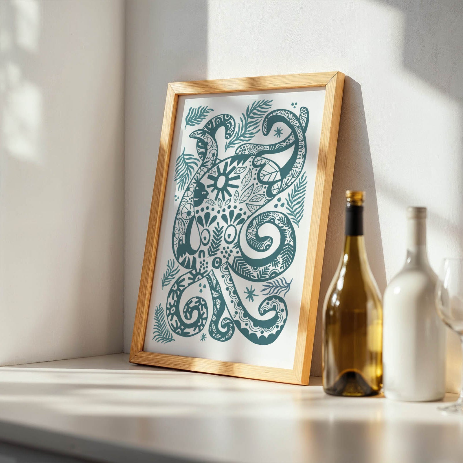 Framed artwork with a decorative design on a shelf with bottles and glasses.