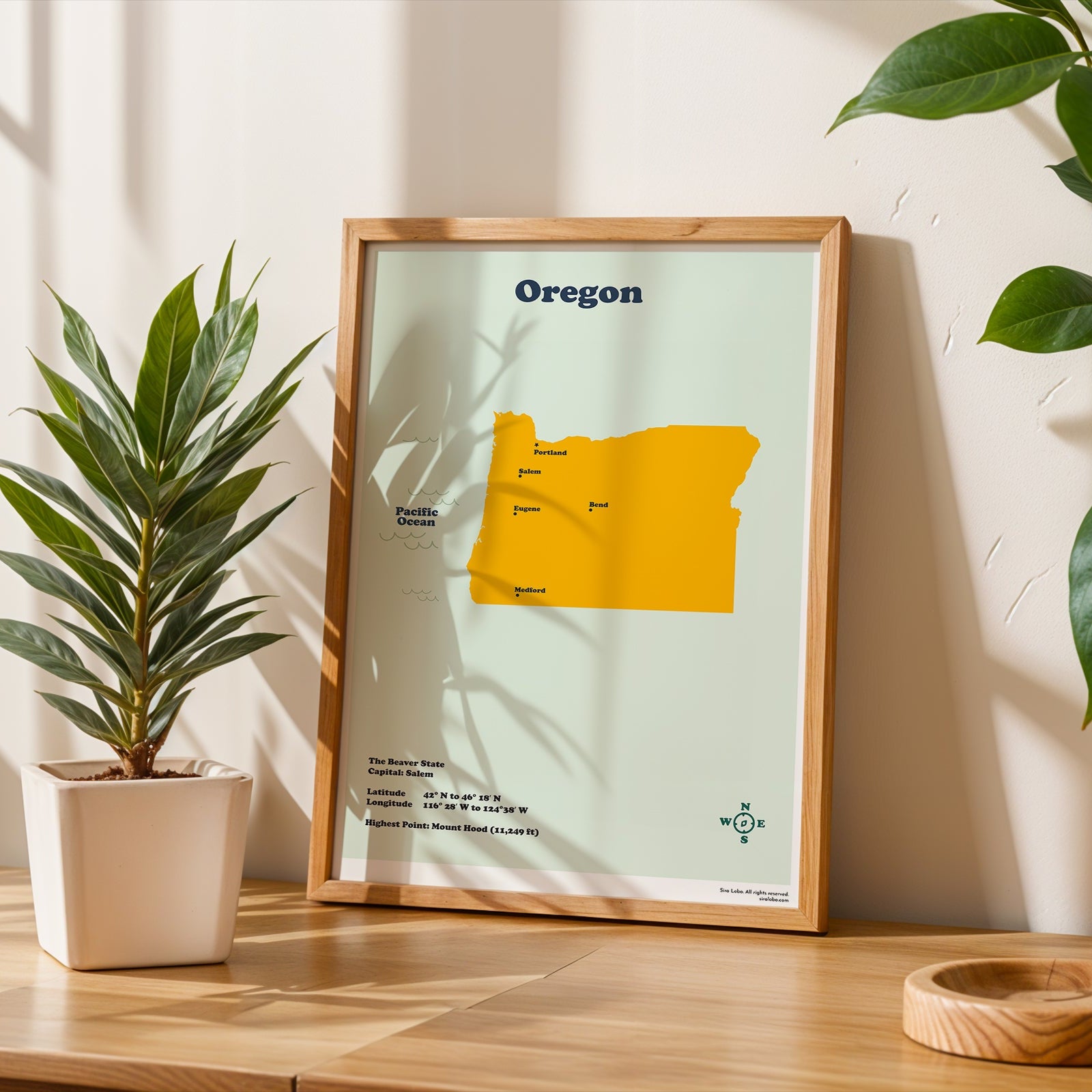 Framed map of Oregon on a wooden surface with plants and a candle