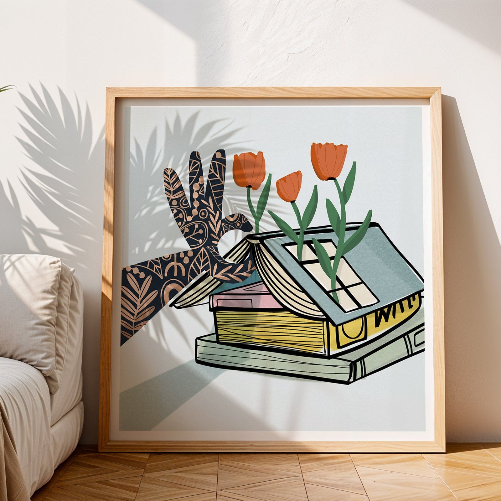 Framed artwork of a hand holding flowers on a book in a living room setting.