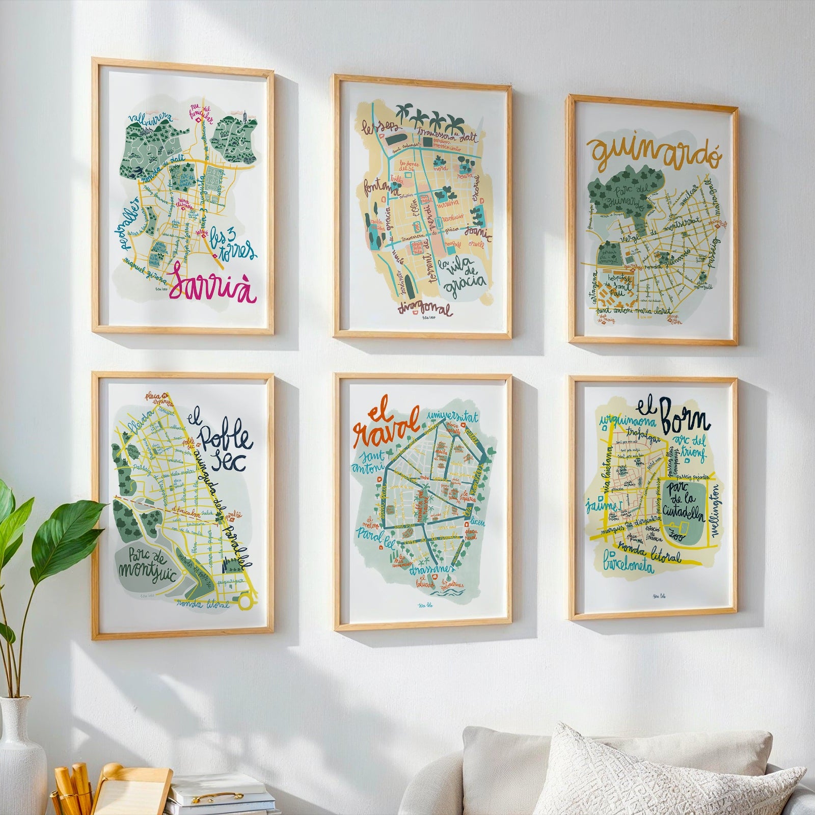 Set of framed maps on a wall in a room with a plant and books.