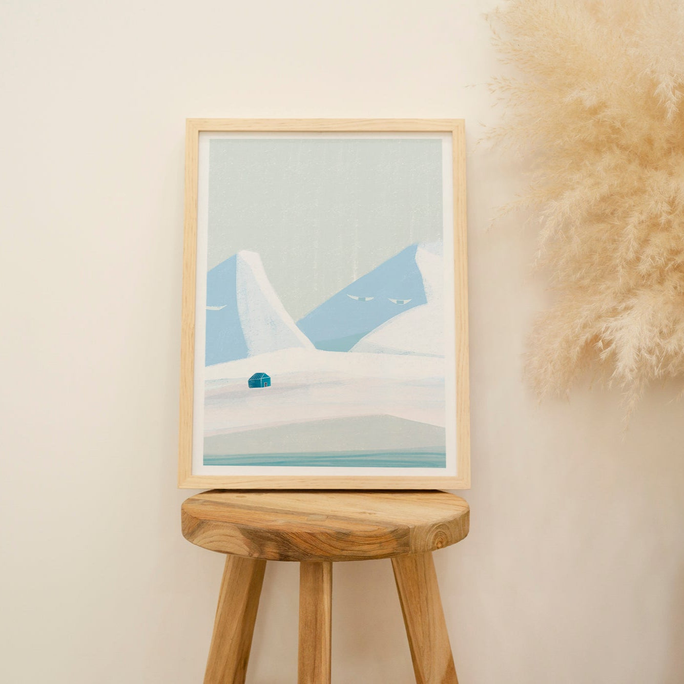 Framed artwork on a wooden stool against a beige wall with decorative elements.