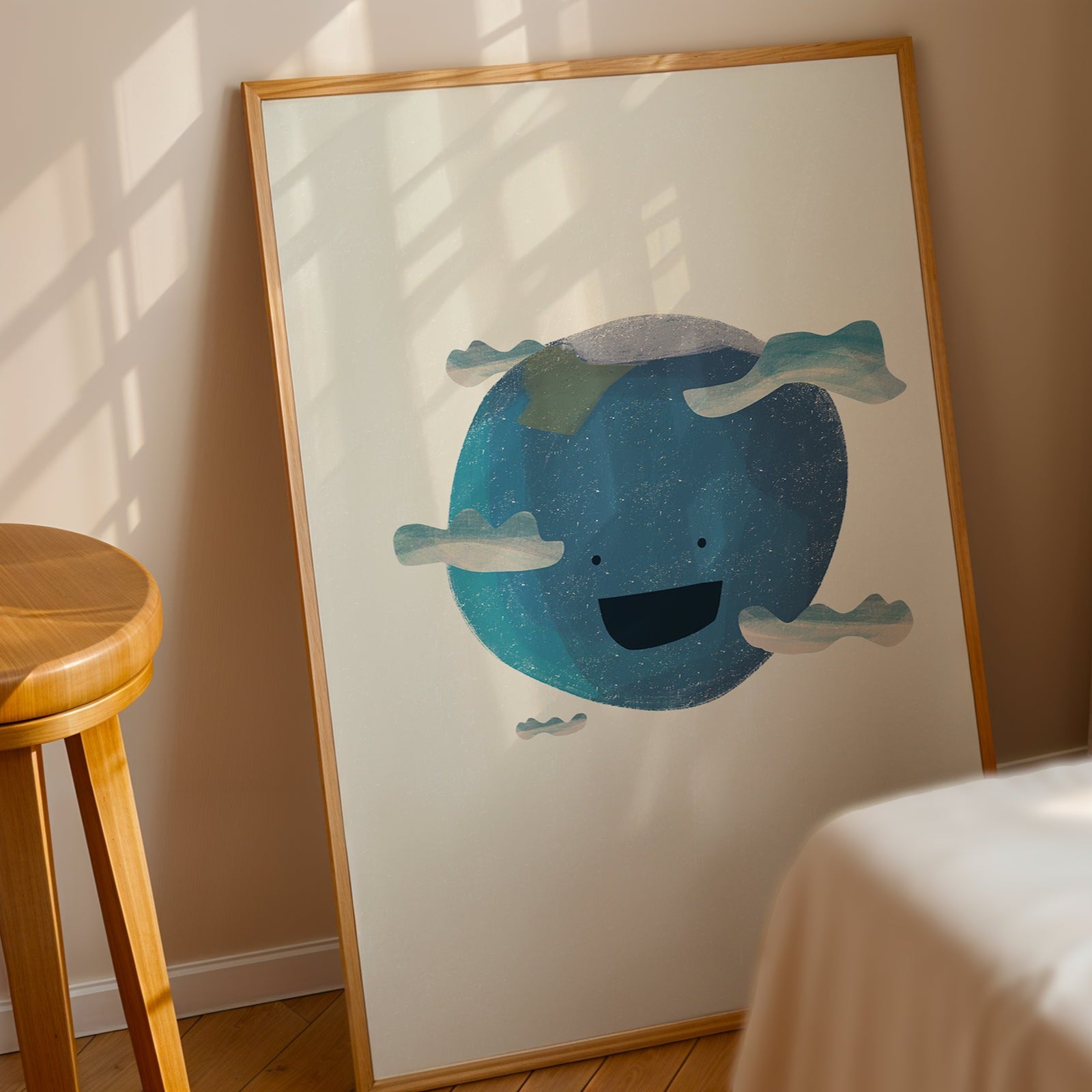 Framed artwork of a blue whale on a white wall with a wooden stool and beige curtain in the background.