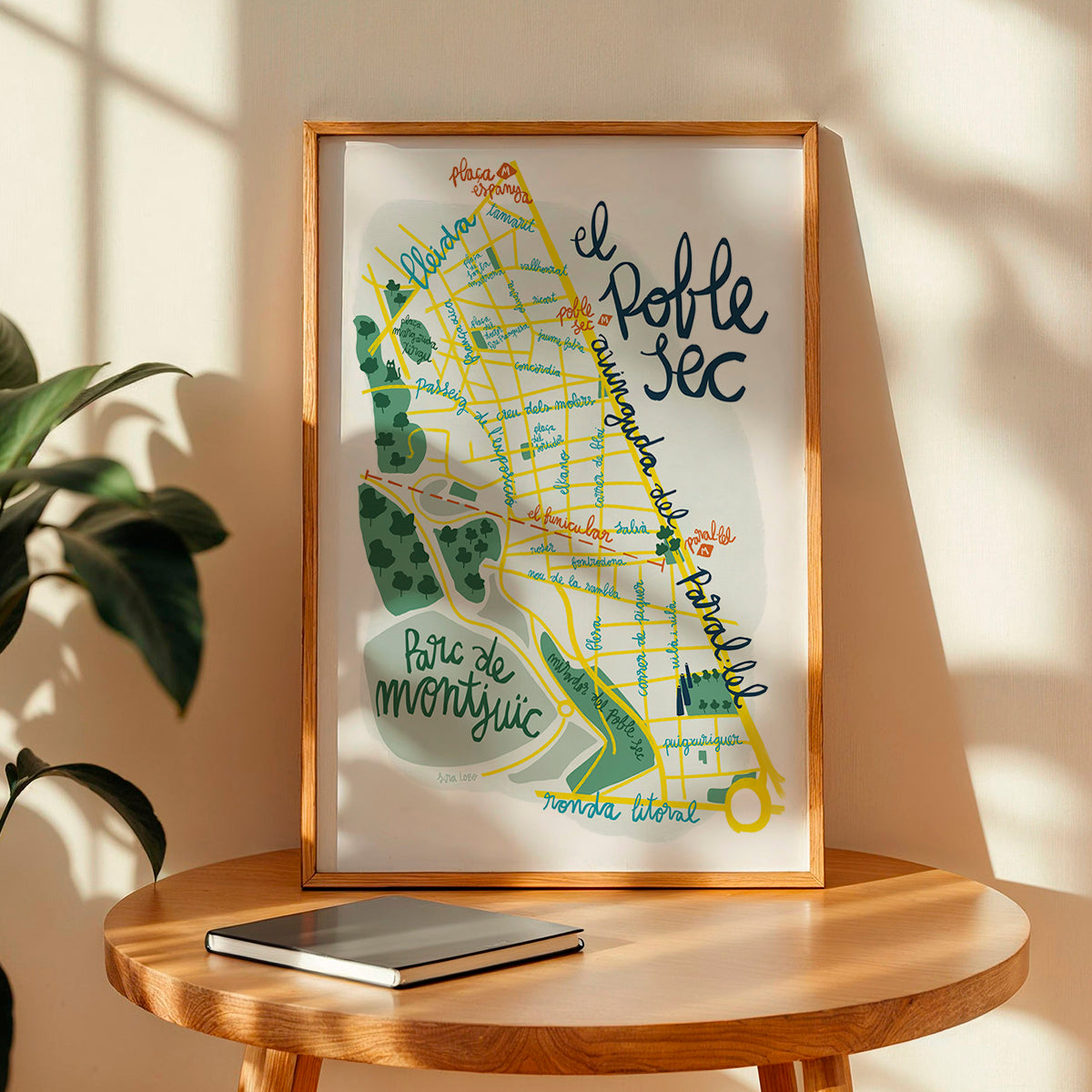 Framed map of Barcelona on a wooden table with a plant in the background