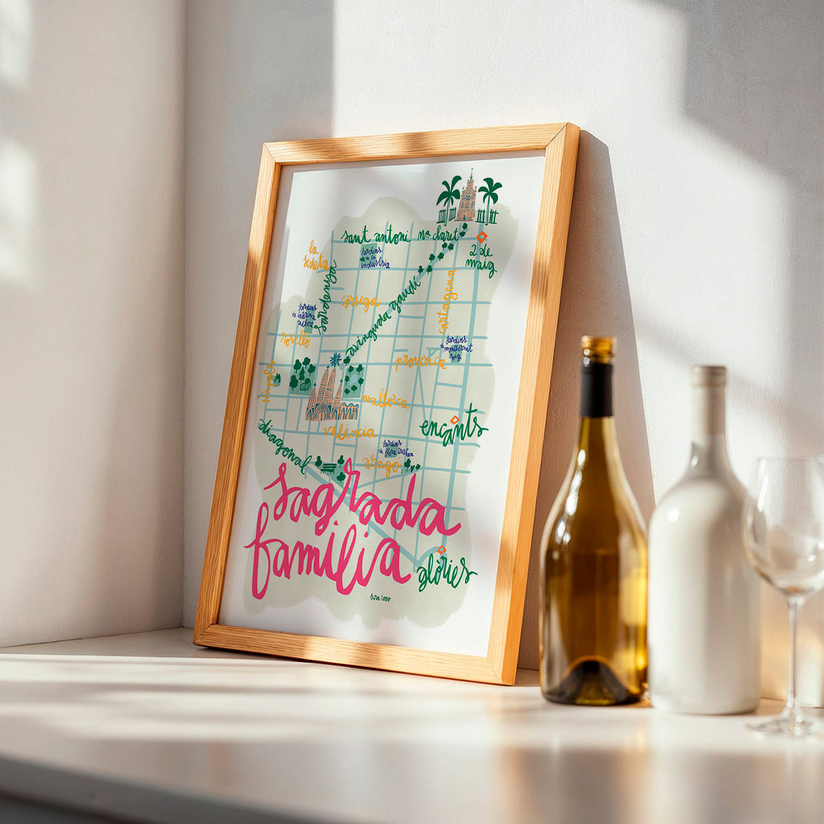 Framed artwork with 'Sagrada Familia' on a shelf with bottles and glasses.