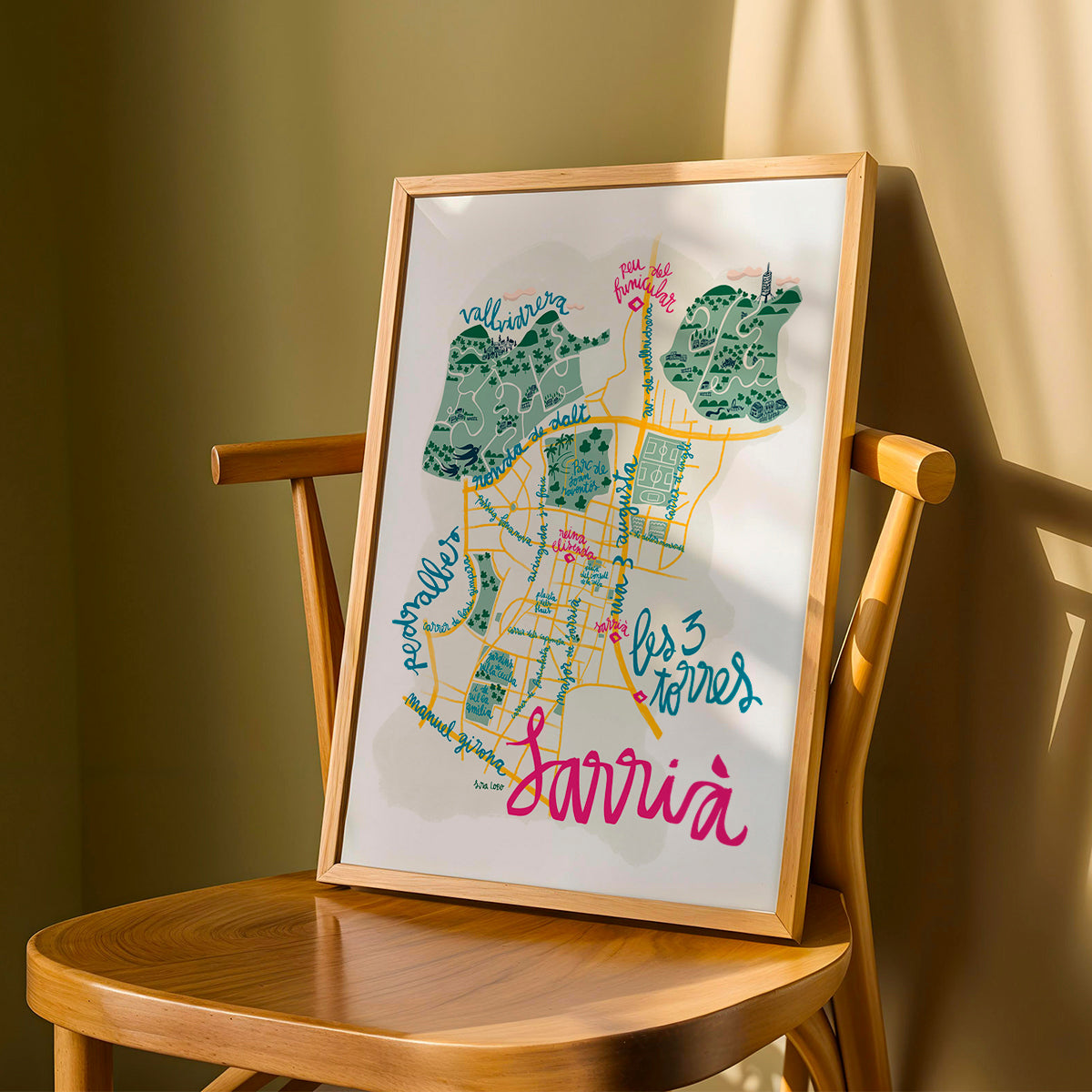 Framed map of Sarrià in Barcelona on a wooden chair against a green wall