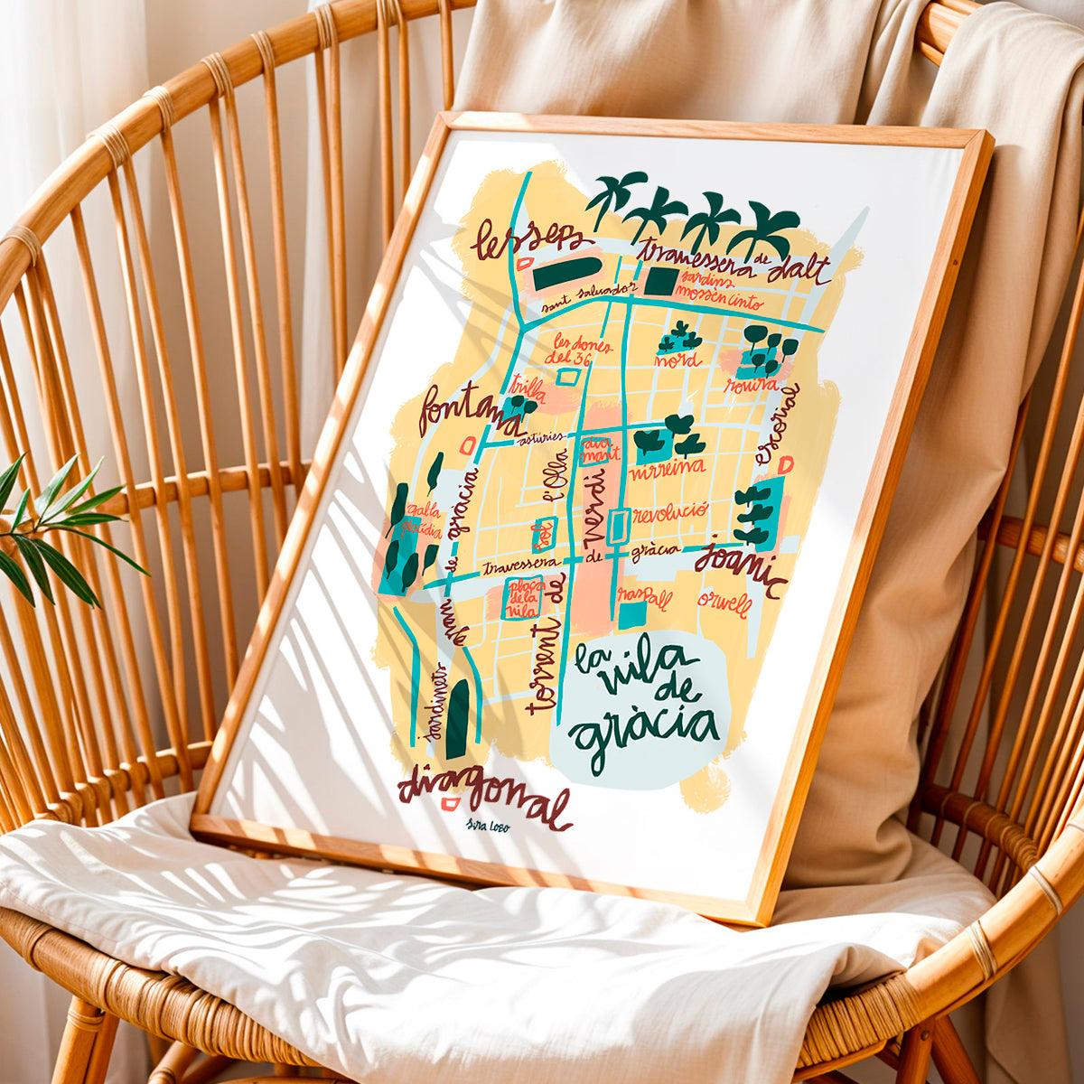 Framed colorful map of Vila de Gràcia in Barcelona on a wicker chair.