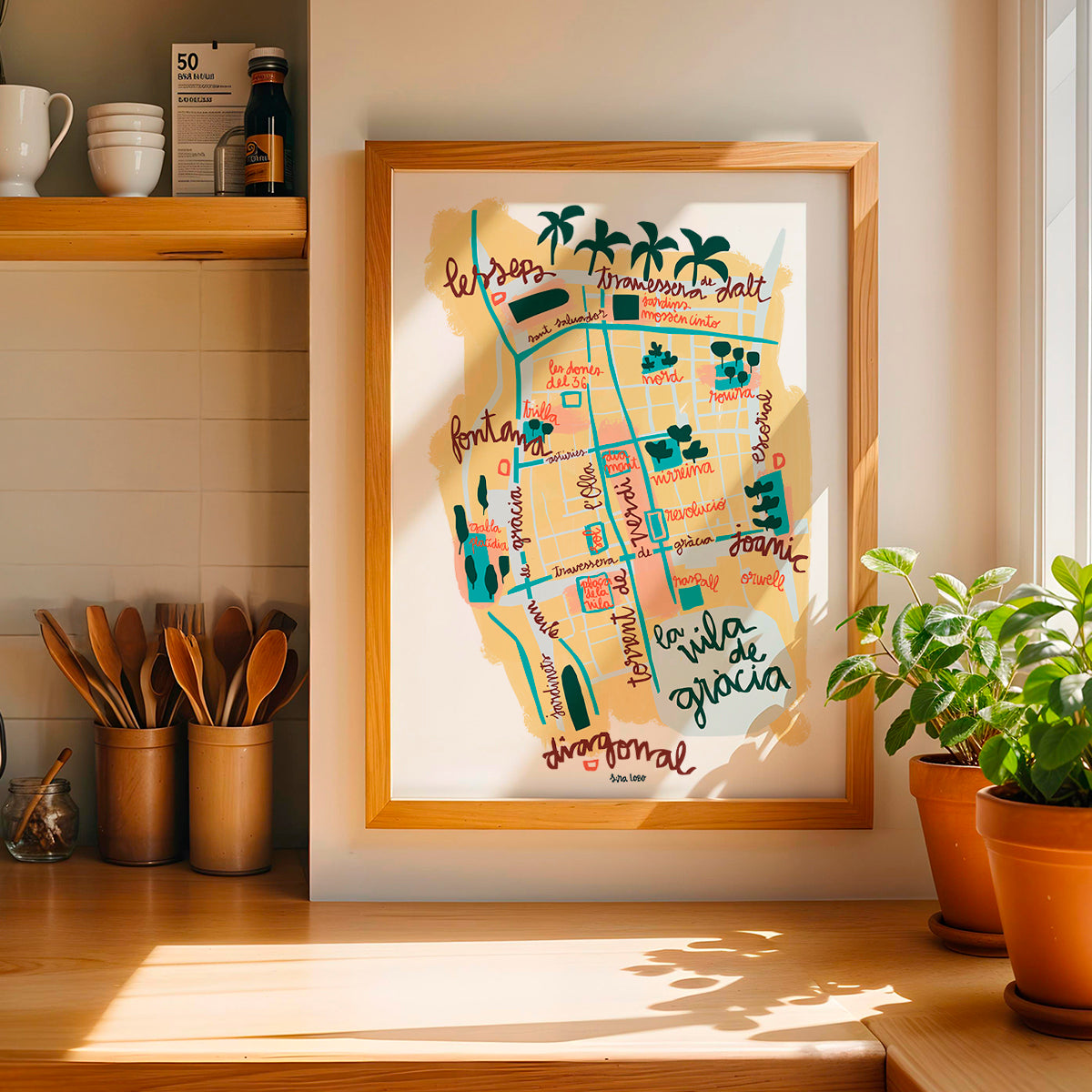 Framed colorful map of Vila de Gràcia in Barcelona on a wall in a kitchen.