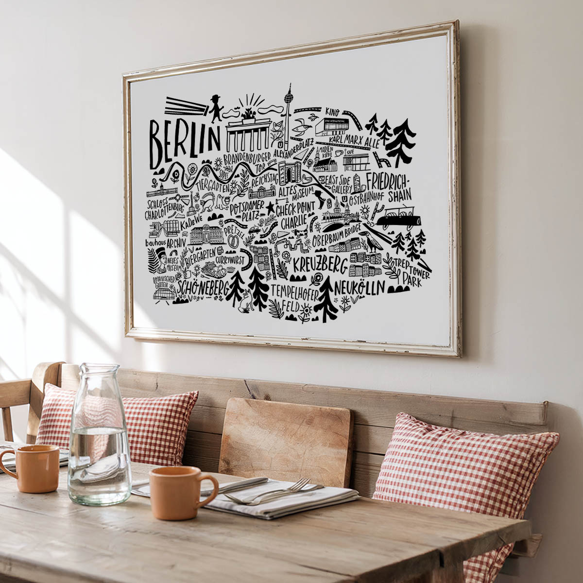 Framed map of Berlin on a wall above a wooden dining table with decor items.