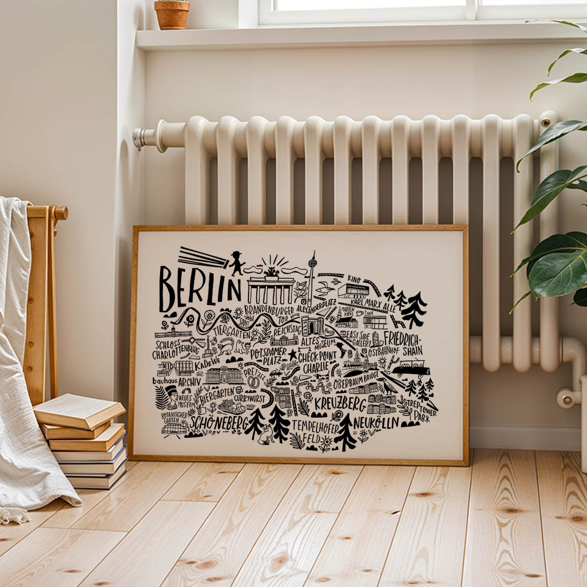 Framed map of Berlin on a wooden floor with a radiator and plant in the background