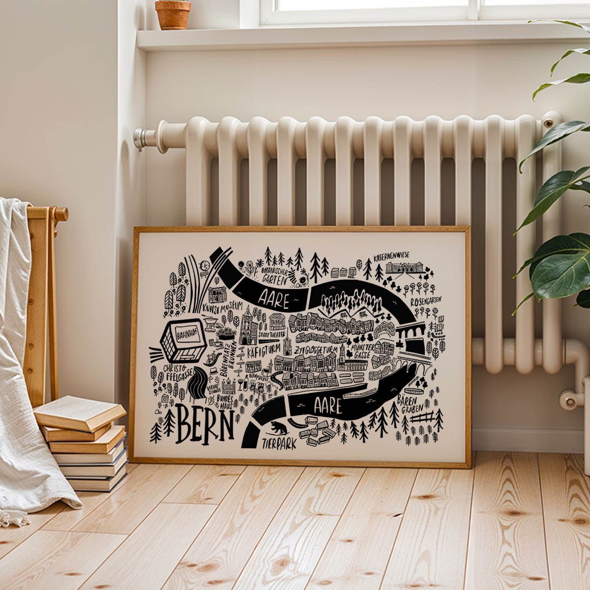 Framed map of Bern on a wall in a room with a radiator and books.