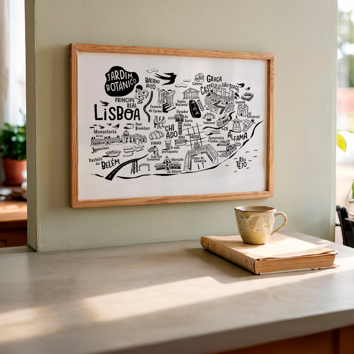 Framed map of Lisbon on a wall above a table with a book and mug.