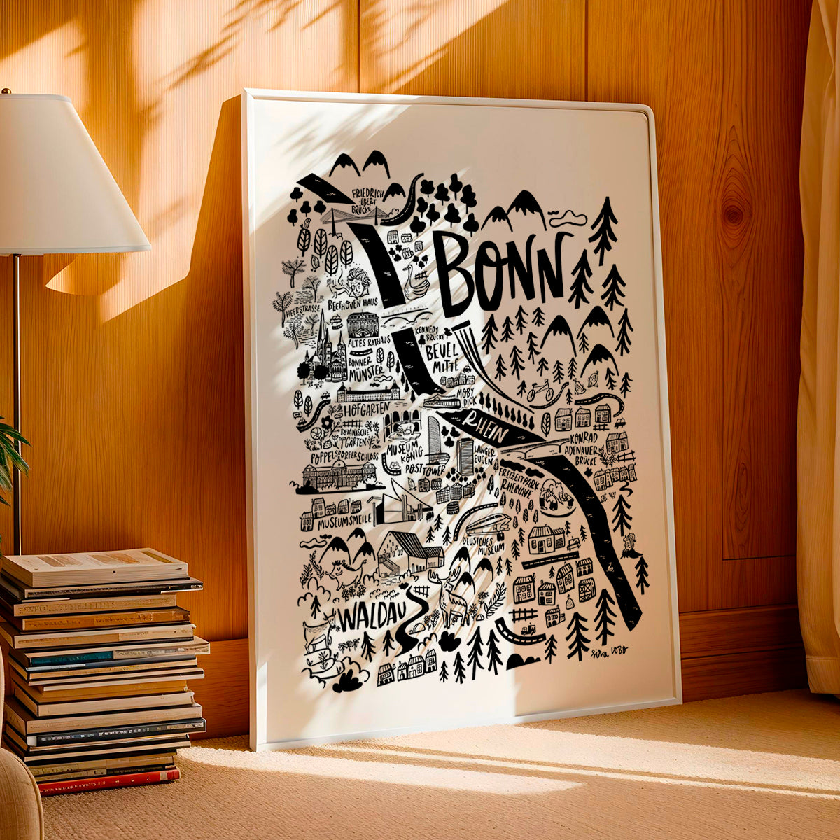 Framed map of Bonn on a wooden wall with books and a lamp in the background