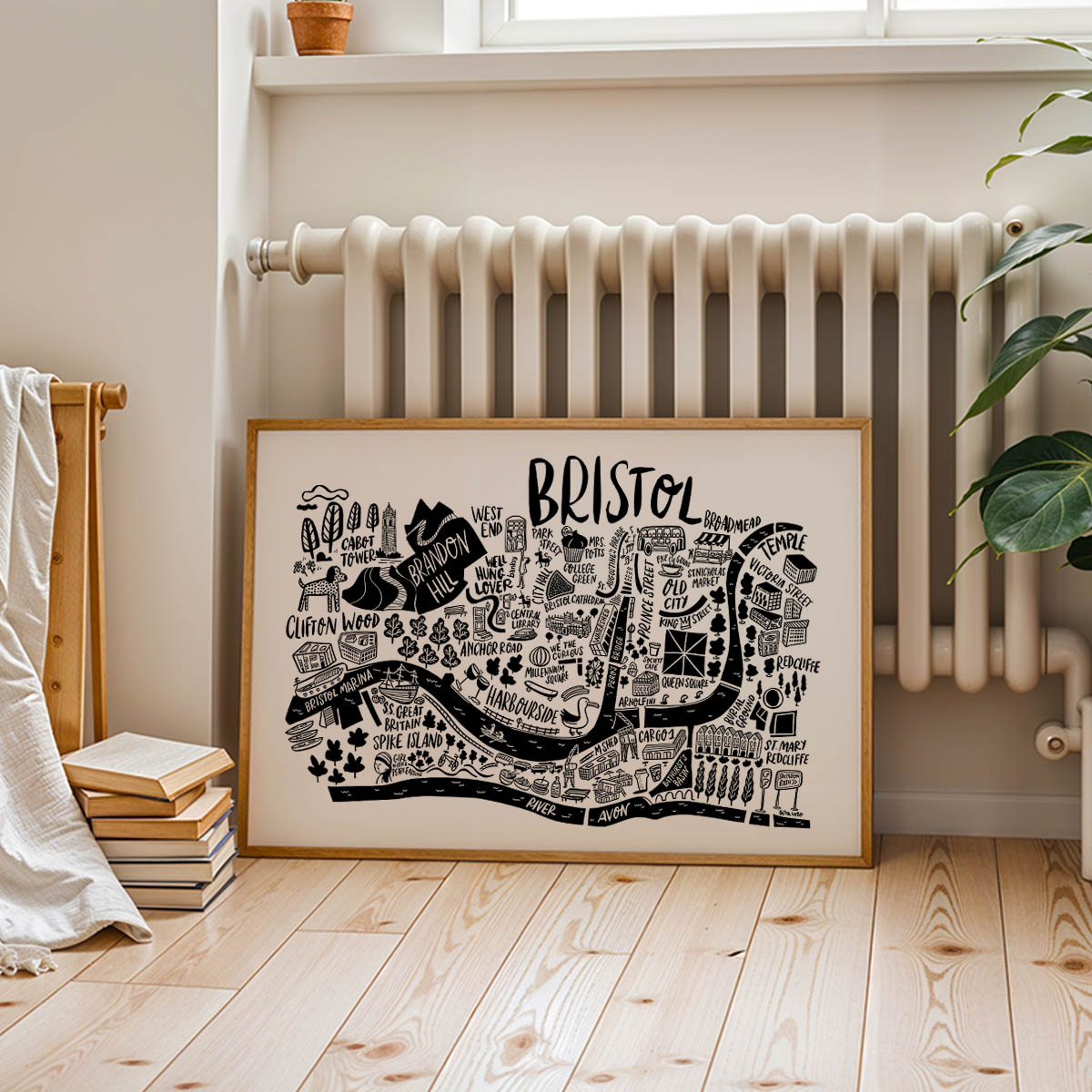 Framed map of Bristol on a wall in a room with a radiator and books.