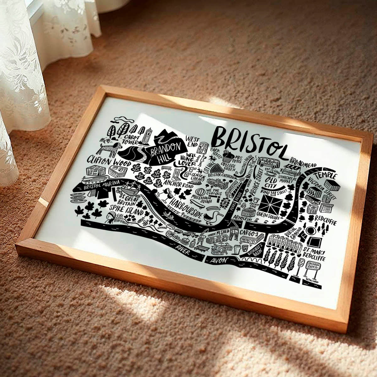 Framed map of Bristol with a wooden frame on a carpeted floor.