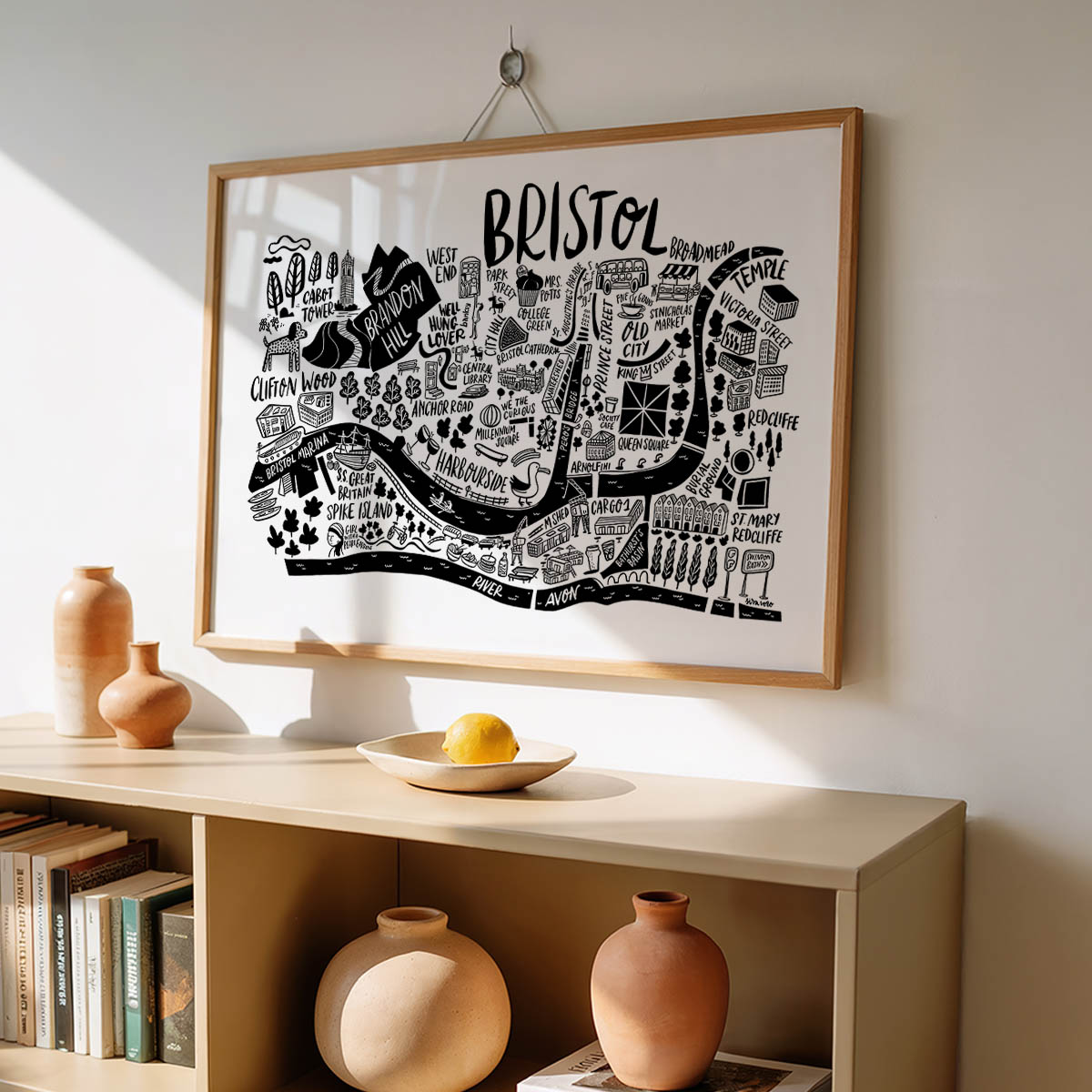 Framed map of Bristol on a wall above a shelf with decorative items.
