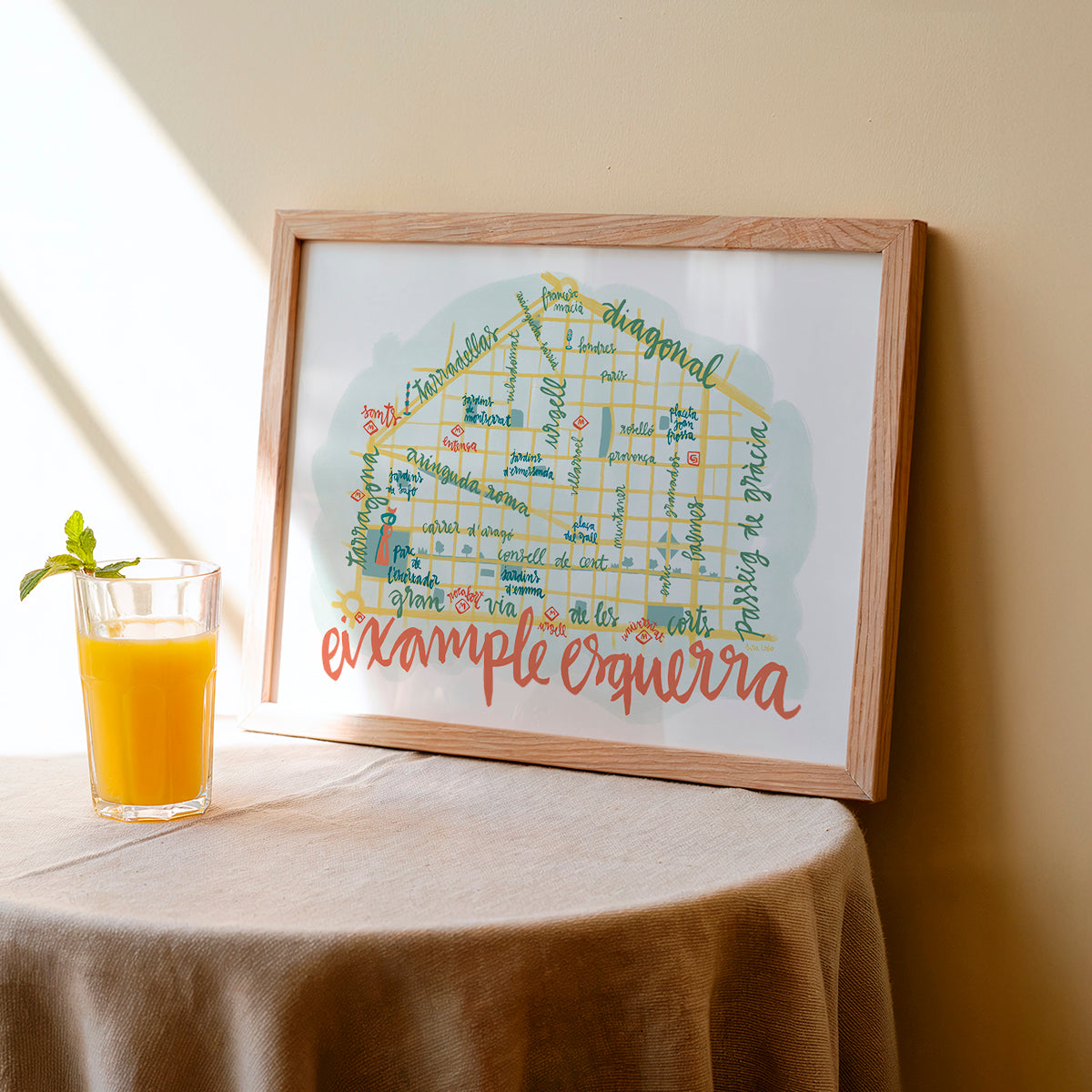 Framed artwork with colorful text on a table next to a glass of orange juice.