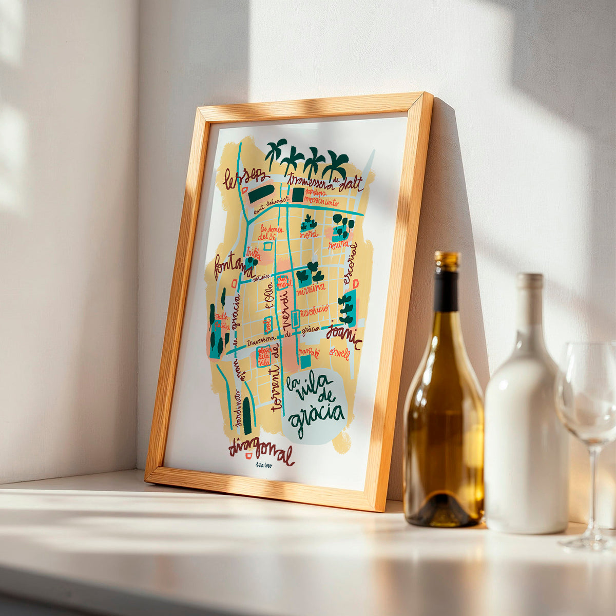 Framed map of Vila de Gràcia in Barcelona on a shelf with wine bottles and glasses
