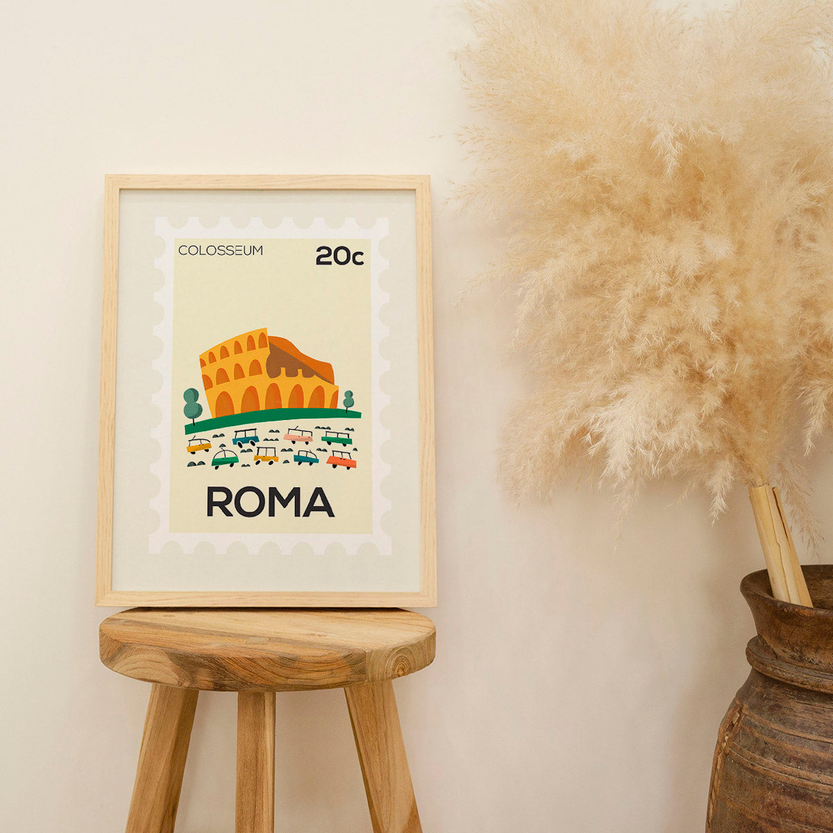 Framed artwork of the Colosseum with 'ROMA' text on a stool against a beige wall.