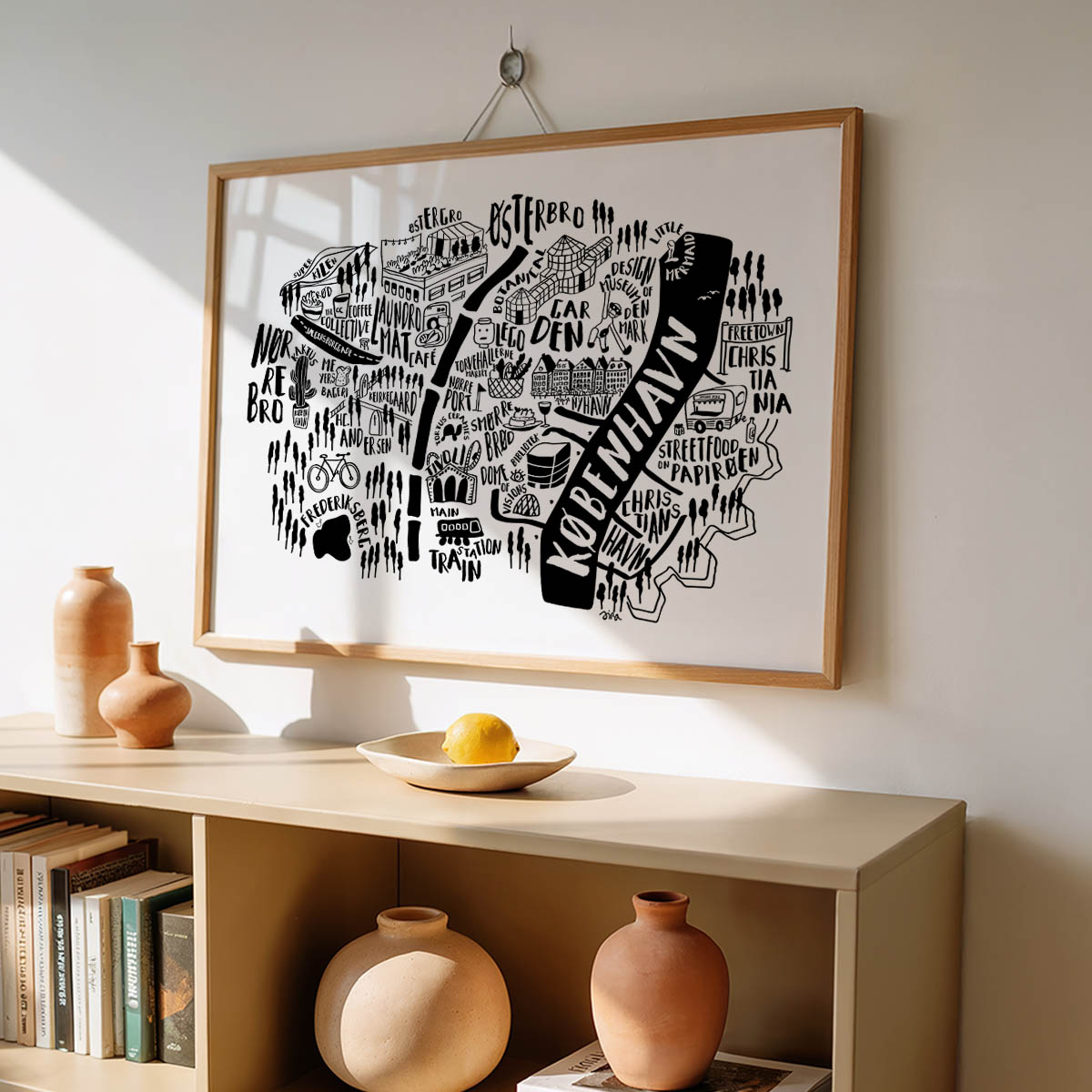 Framed map of Koeveldam on a wall above a shelf with decorative items.