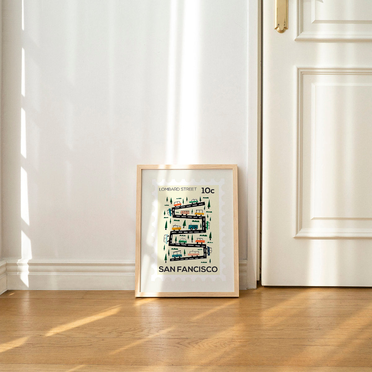 Framed artwork of a map of San Francisco on a wall with sunlight filtering through curtains.