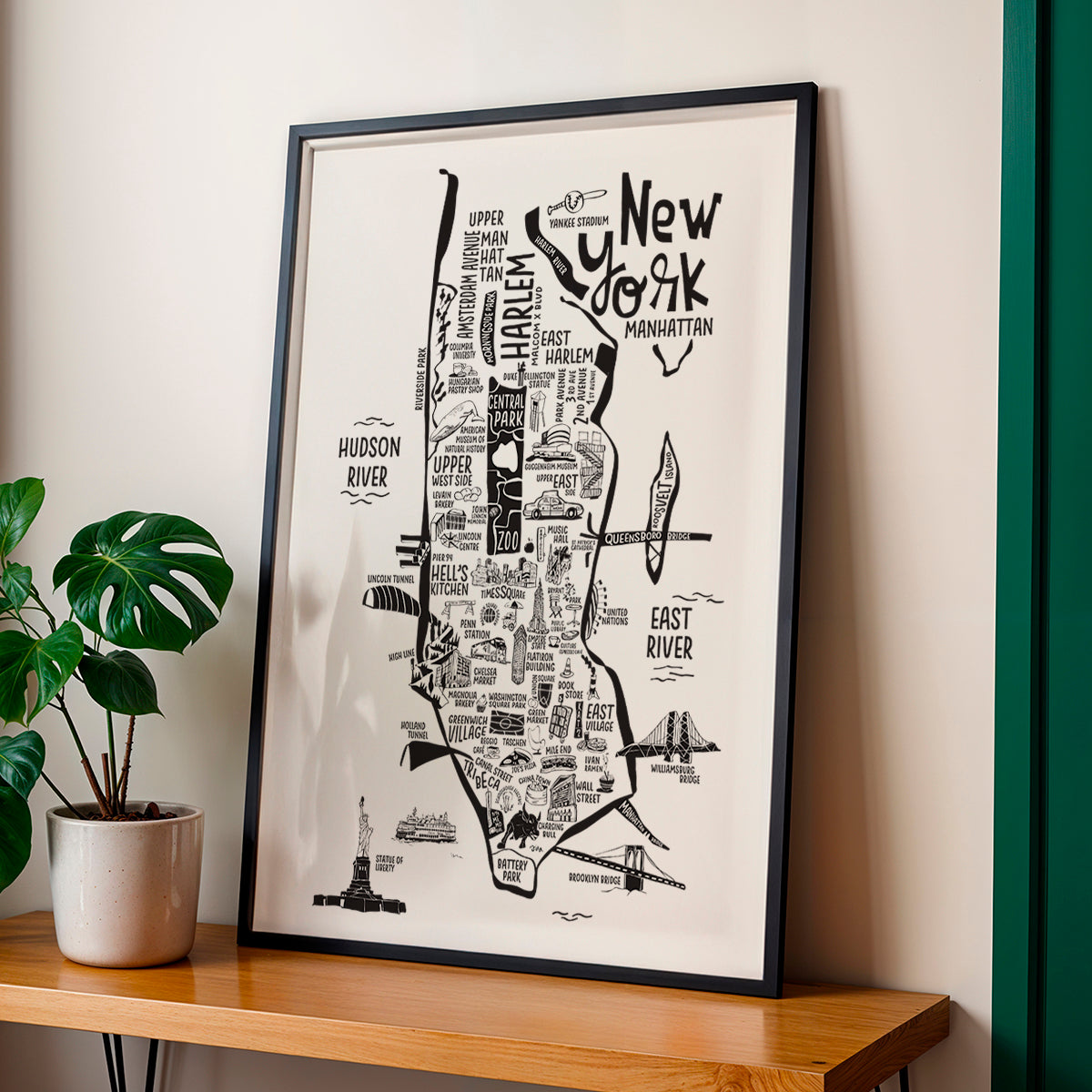 Framed map of New York City on a wall with a plant beside it