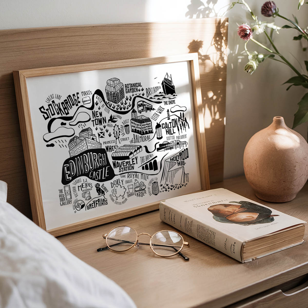 Framed map of Edinburgh on a wooden surface with a book and glasses.