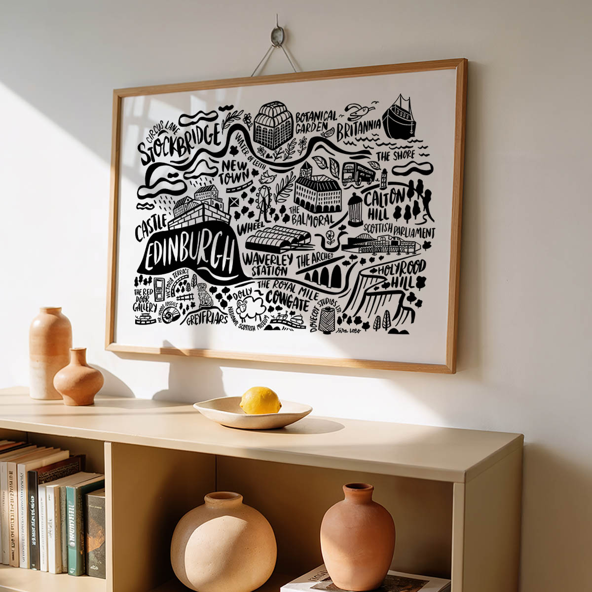 Framed map of Edinburgh on a wall above a shelf with decorative items.