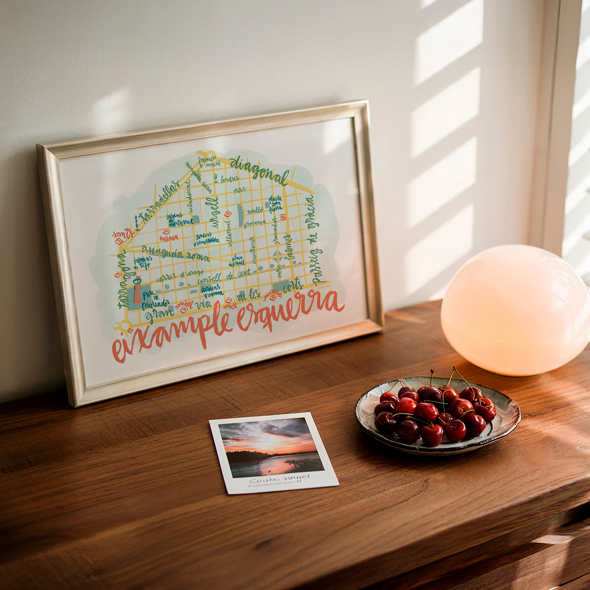 Framed map on a wooden surface with cherries and a photo