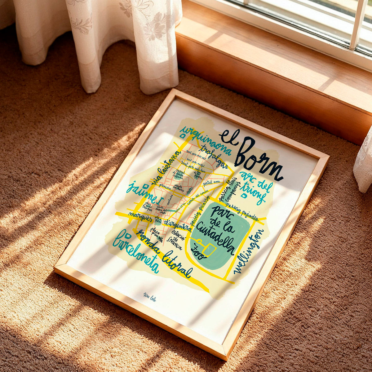 Framed map of El Born district in Barcelona on a carpeted floor with sunlight casting shadows.