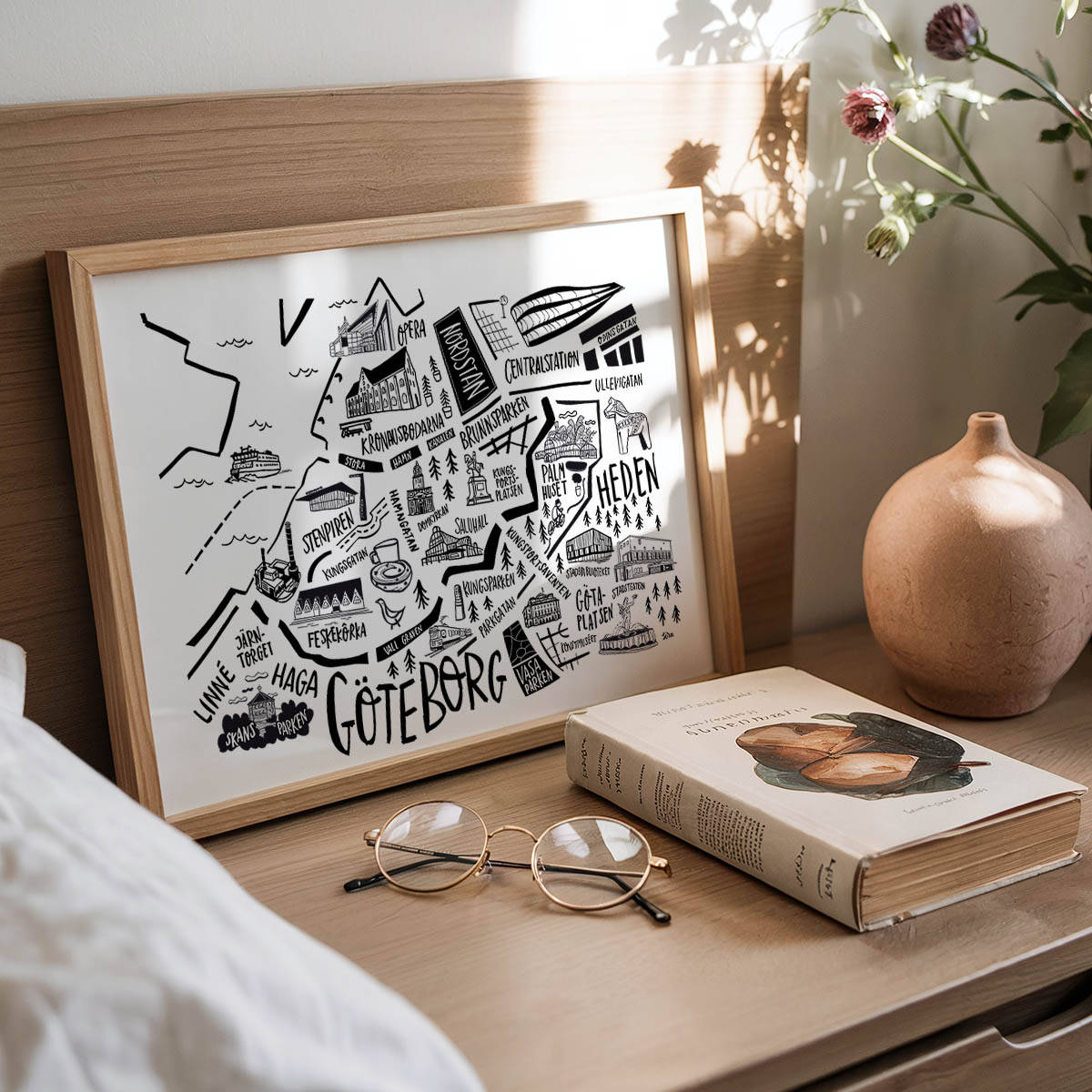Framed map of Gothenburg on a wooden surface with a book and glasses.