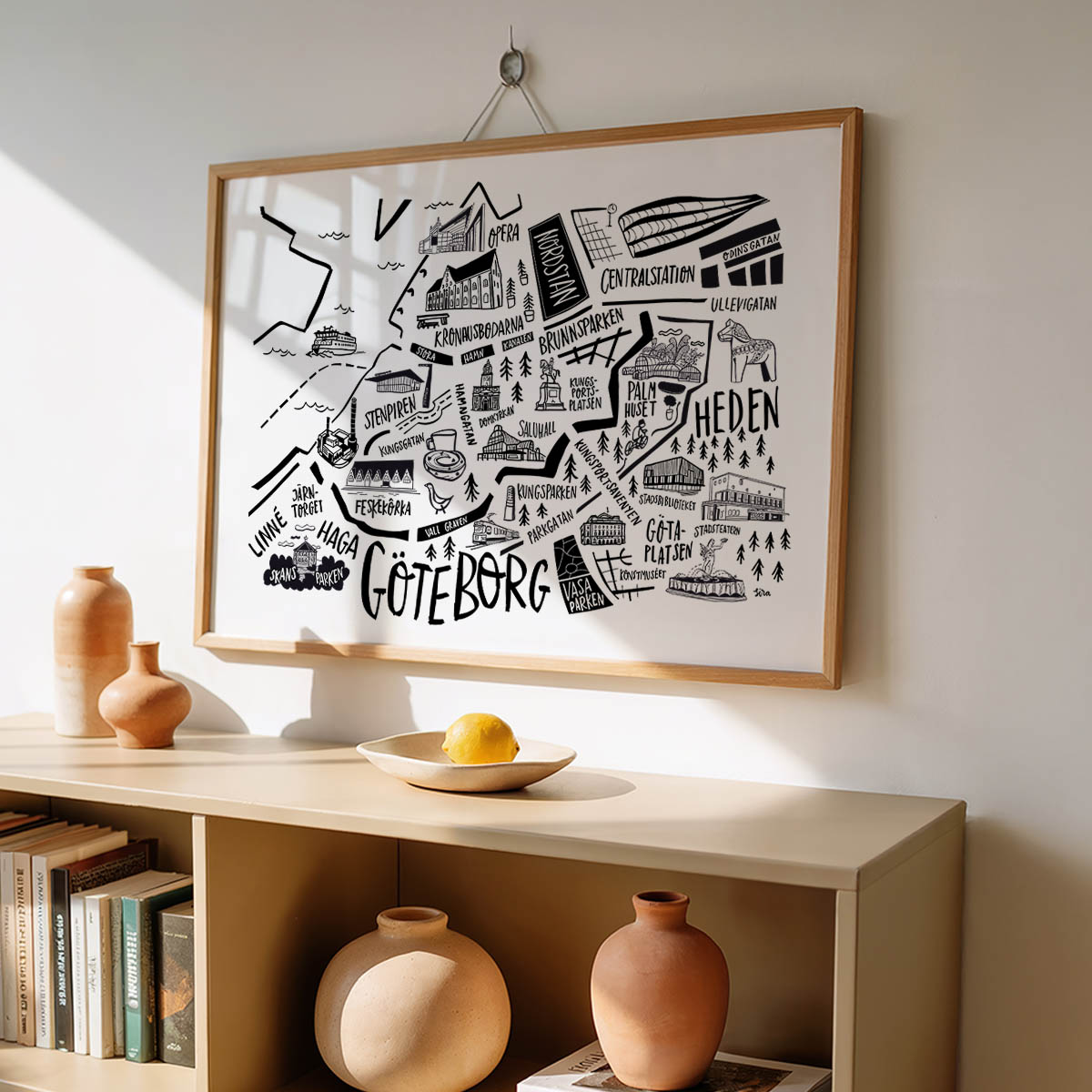 Framed map of Gothenburg on a wall above a wooden shelf with decorative items.