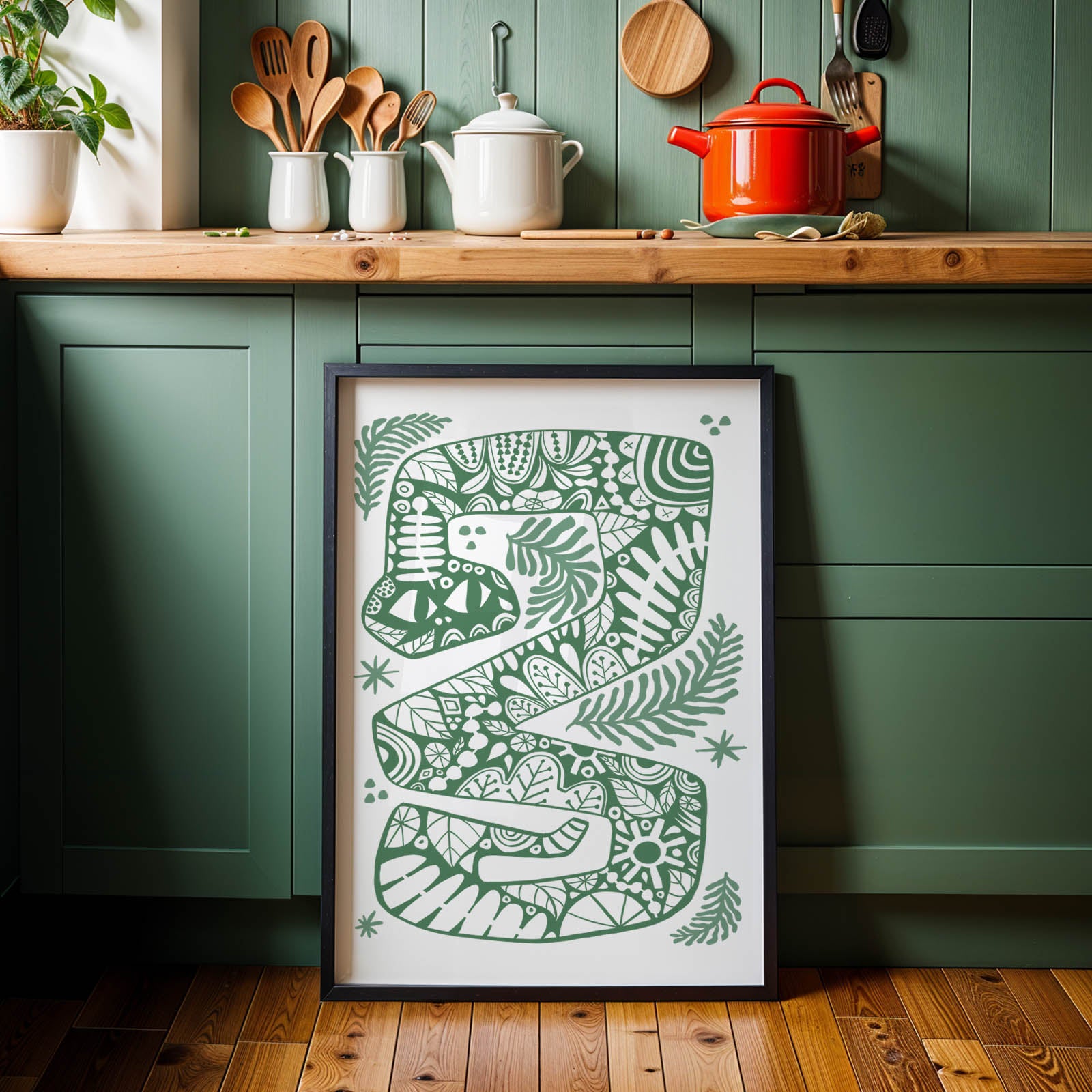 Framed green artwork on a kitchen wall with wooden cabinets and decorative items.