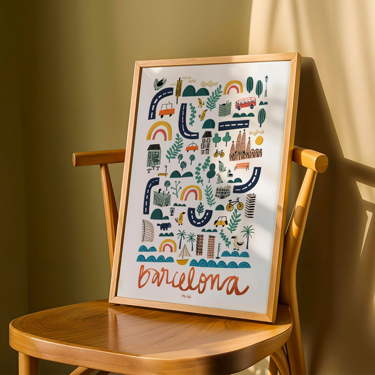Framed artwork with 'Barcelona' design on a wooden chair against a green wall.