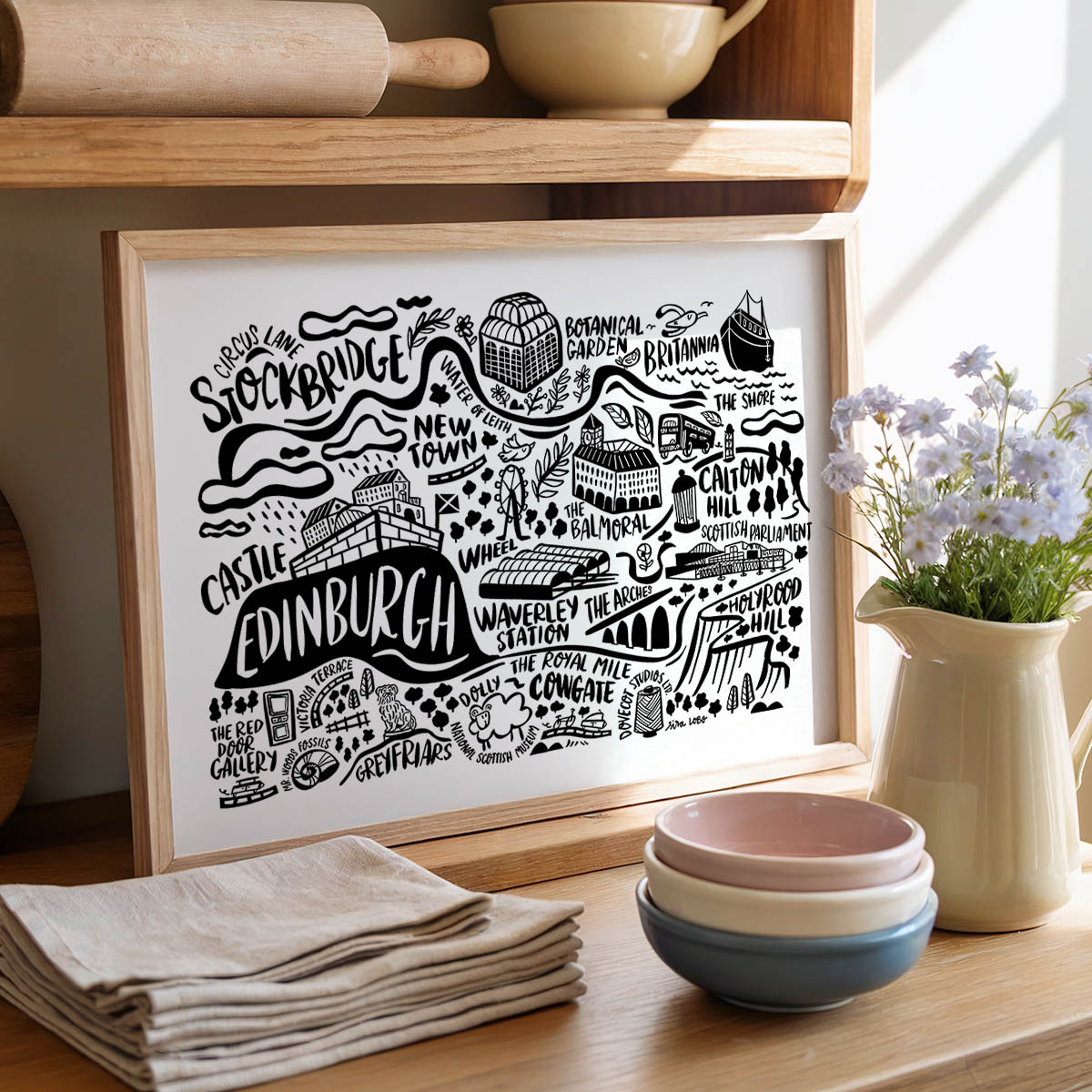 Framed artwork of Edinburgh with kitchen items on a wooden shelf