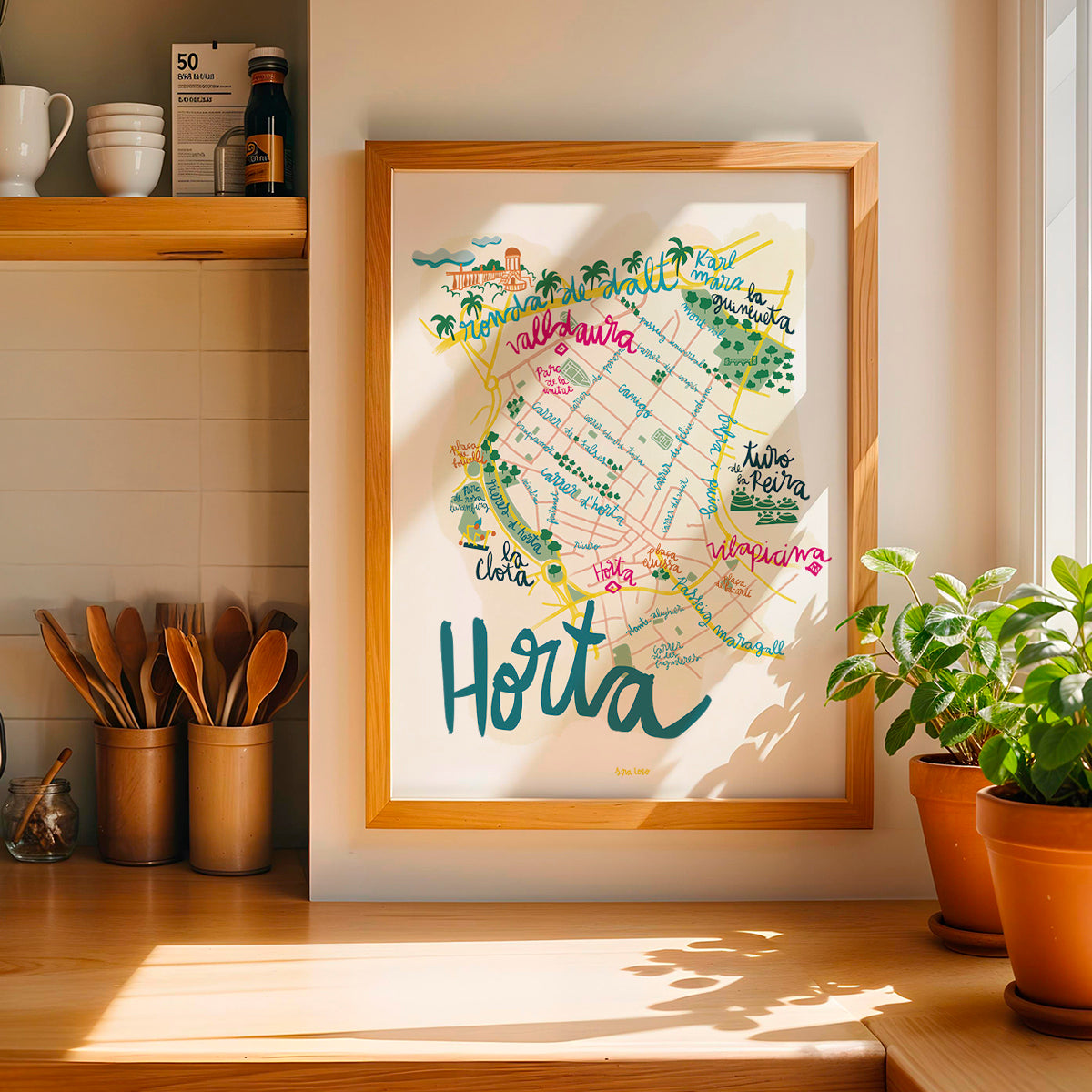 Framed map of Horta on a kitchen wall with plants and utensils below