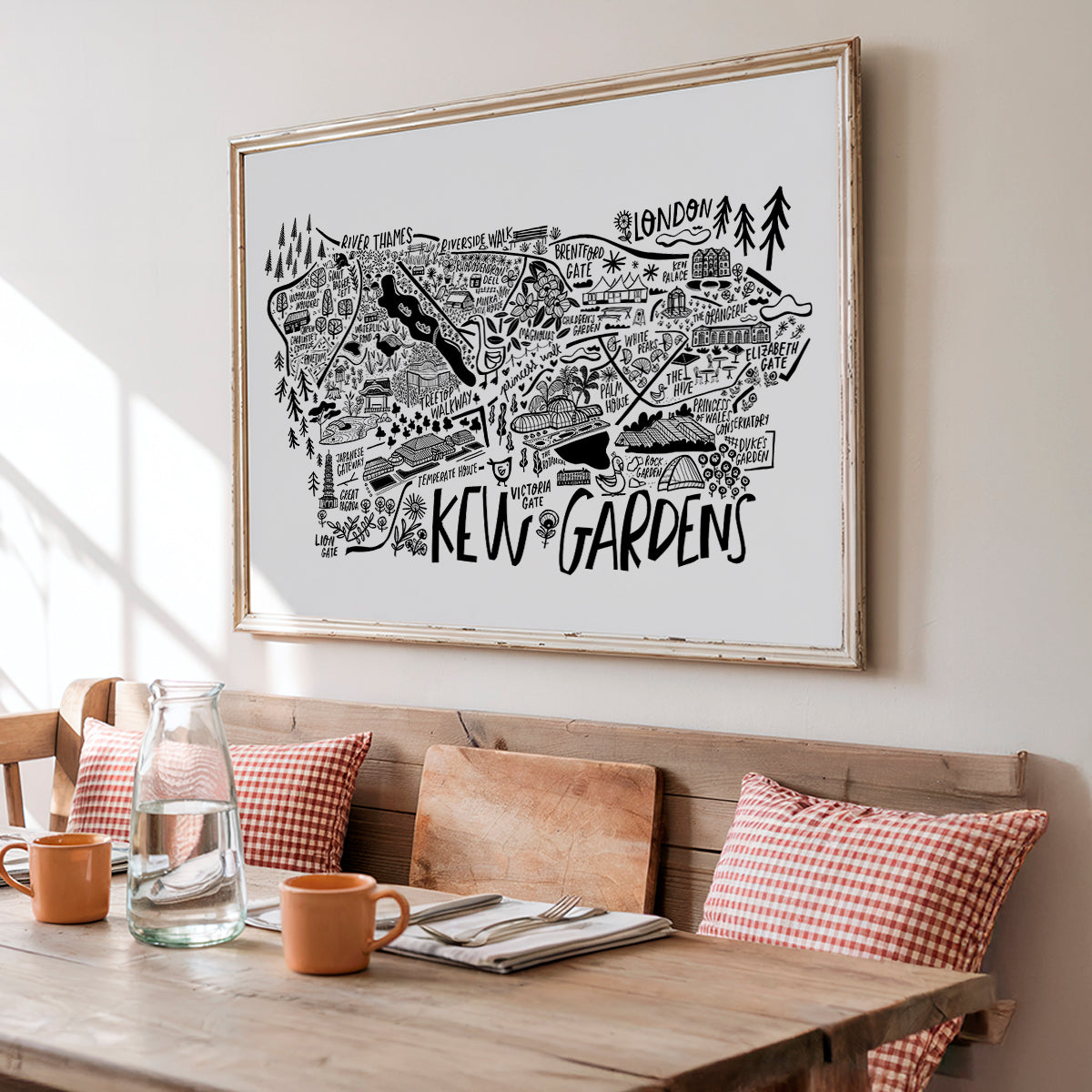 Framed map of Kew Gardens above a wooden table with a bench and cushions.