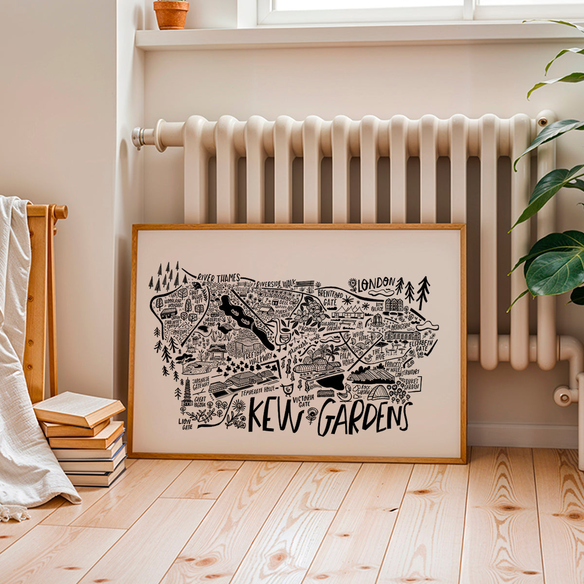 Framed map of Kew Gardens on a wall in a room with a radiator and books.